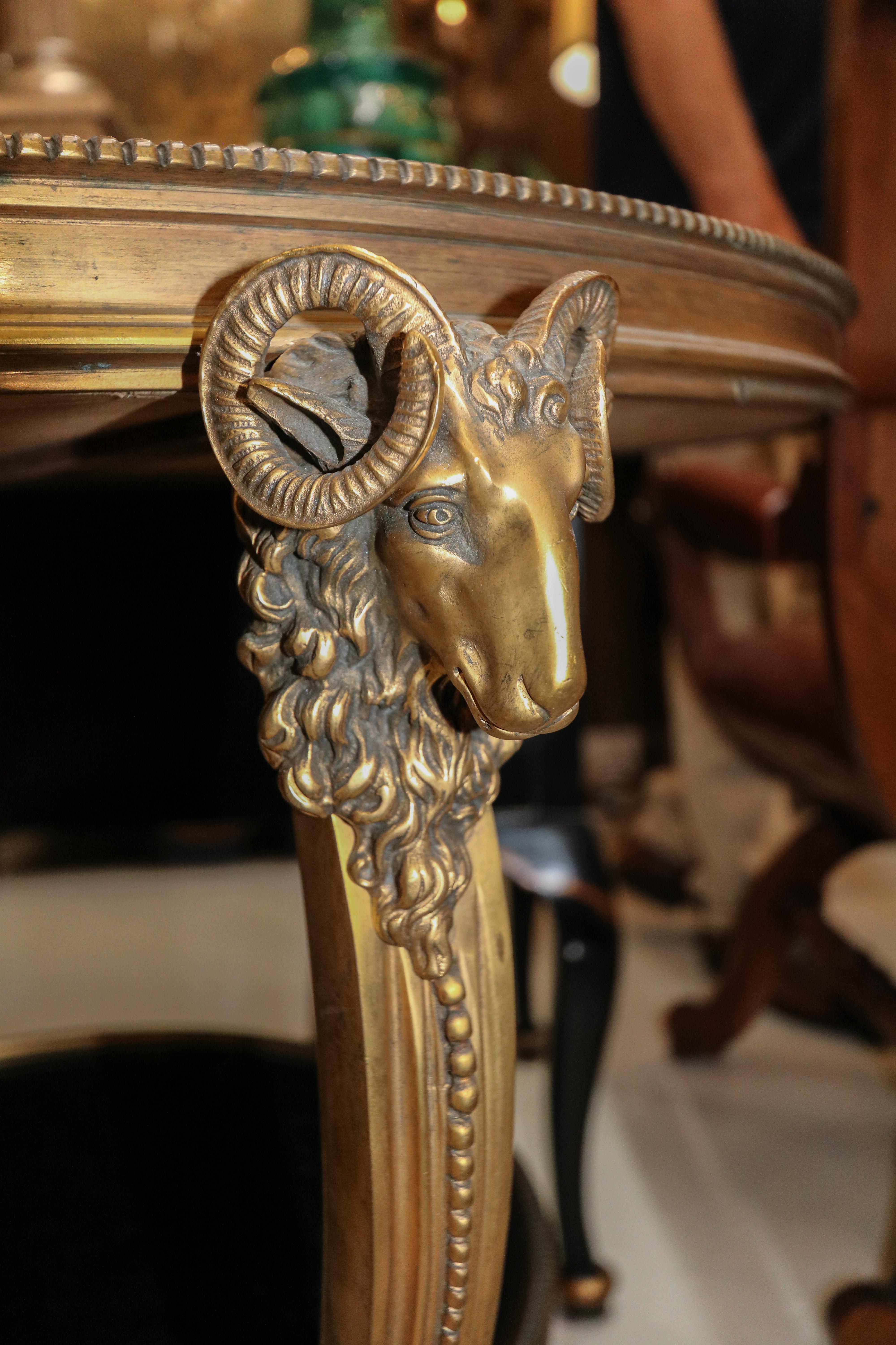 French Gueridon side table from the 1920s in gilt bronze with ram's head details and hoofed feet with black marble top and shelf.