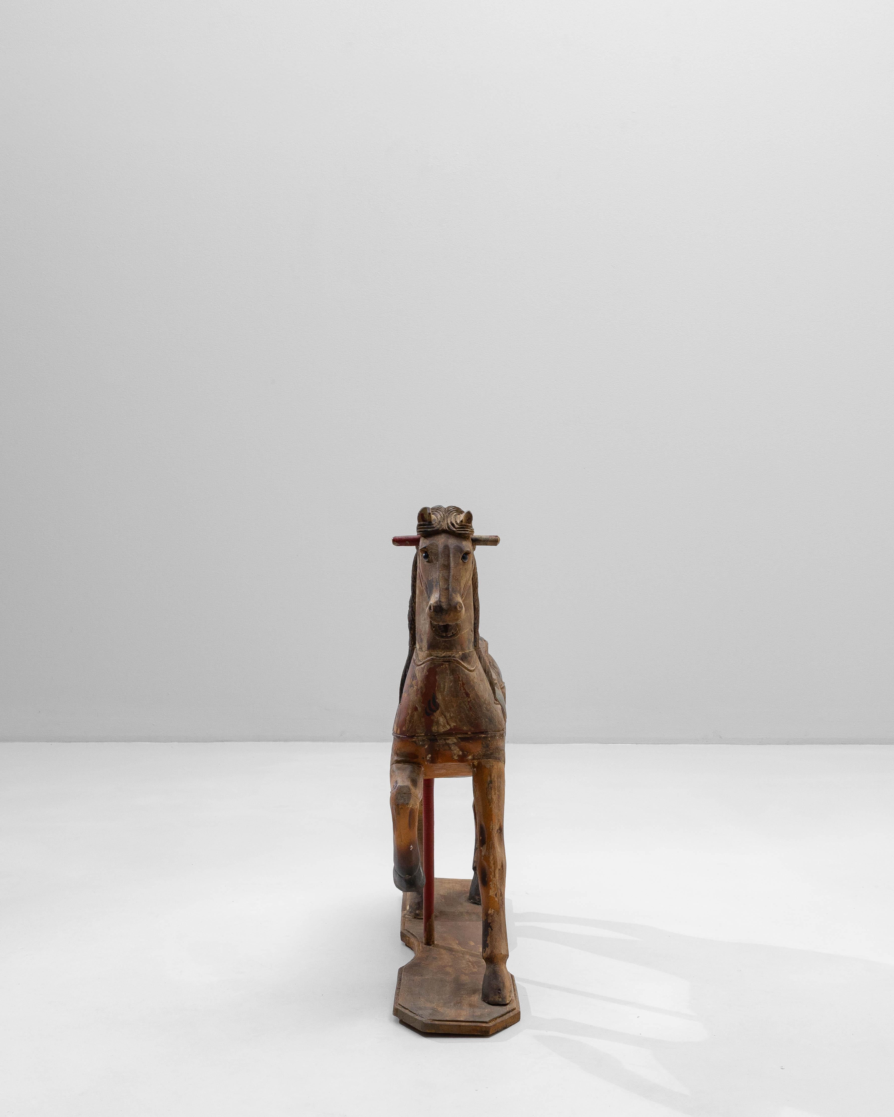 Questo cavallo da giostra francese degli anni '20 intagliato a mano in legno è un'affascinante reliquia dell'artigianato da fiera dei primi del Novecento, che conserva un carattere e un fascino notevoli. Scolpito con dettagli espressivi, il cavallo