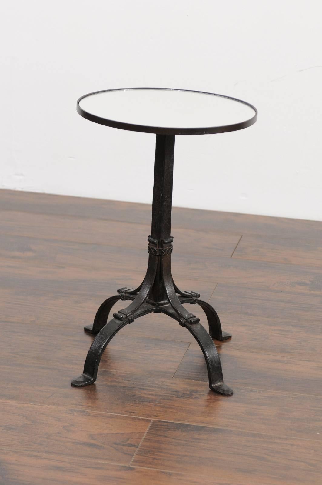 A French black iron round drink table from the early 20th century, with new mirrored top. Born during the Roaring Twenties, this French drink table features a circular top, securing a new custom-made clear mirror. The table is raised on an iron