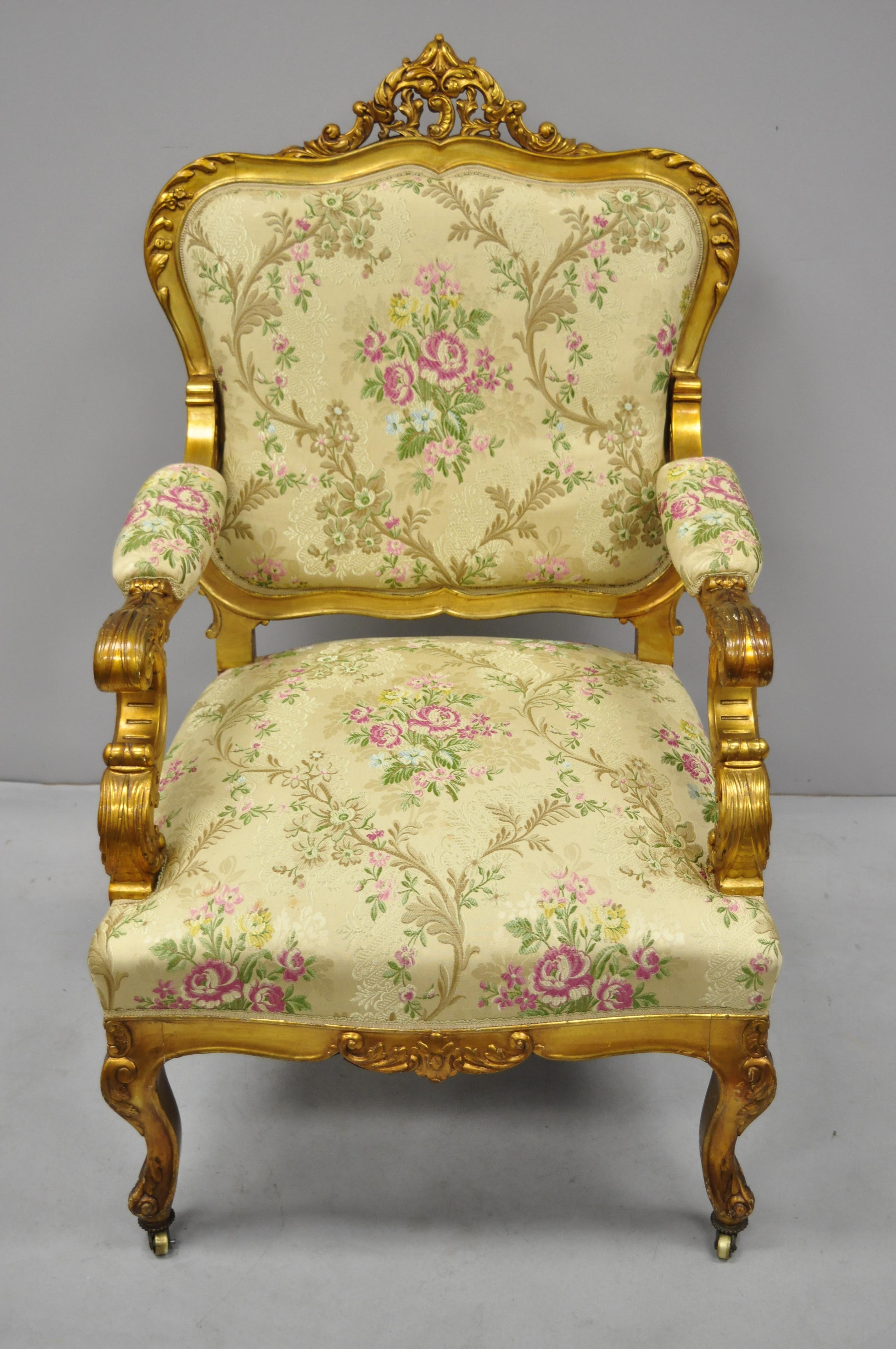 1920s French Louis XV Rococo style gold gilt parlor armchair. Item features brass rolling casters, distressed gold finish, gold fabric with pink flowers, solid wood construction, upholstered armrests, nicely carved details, cabriole legs, very nice