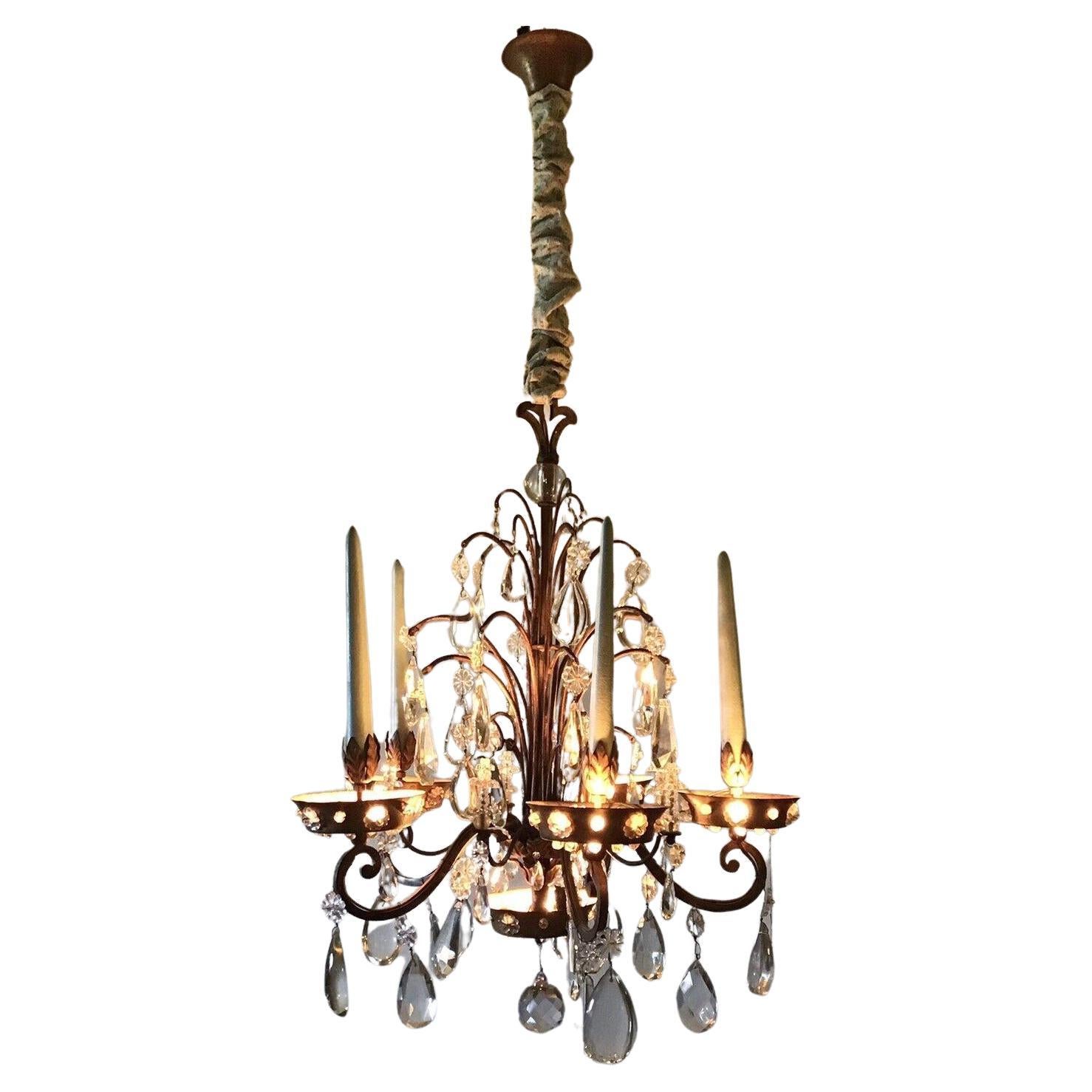 This is a very special chandelier. 1920's French Louis XVI Rococo Form Crystal w/ Wrought Iron Chandelier. There is electric light emanating from the crystal studded bobesche. I was told chandeliers of this type were used in the Rococo era as a