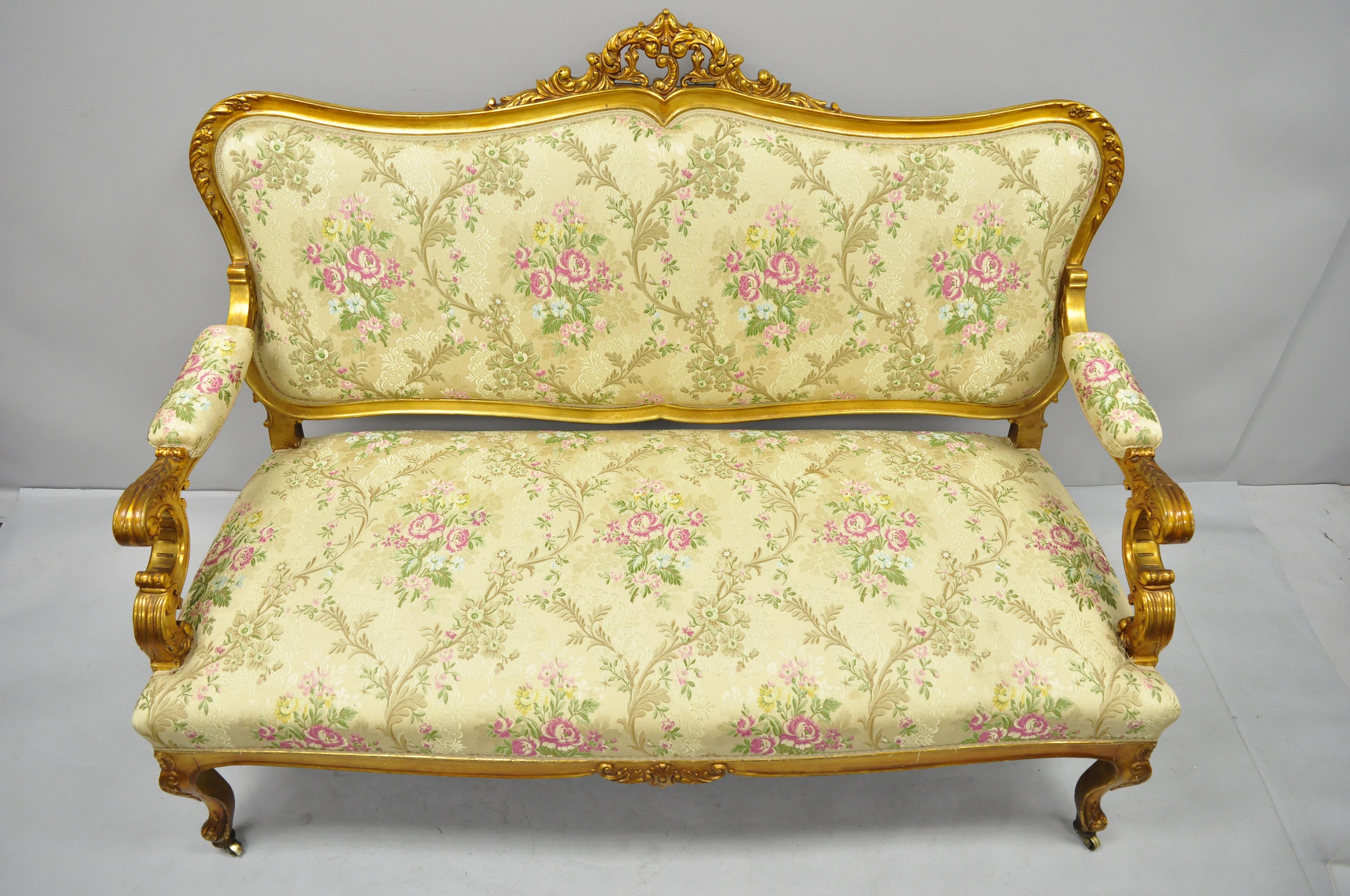 1920s, French, Louis XV style gold gilt settee. Item features rolling casters, floral patterned upholstery, solid wood construction, upholstered armrests, distressed gold finish, nicely carved details and cabriole legs; a very nice antique item.