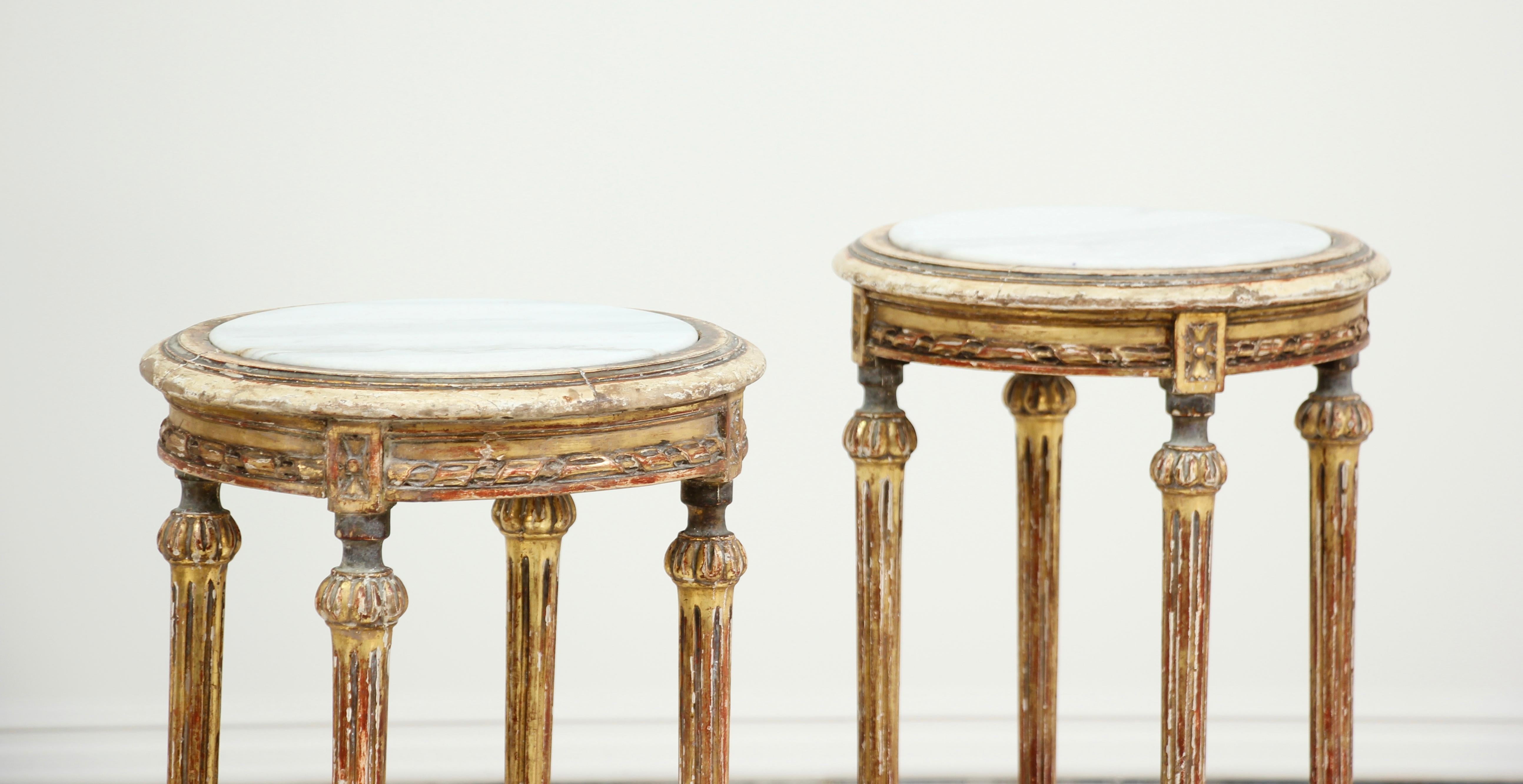 Beautiful, 1920s French Louis XVI style carved giltwood pedestal or side tables with Carrara marble tops. The original gilt finish is beautifully and naturally distressed. The tables are sturdy and strong, ready for many more years of use and