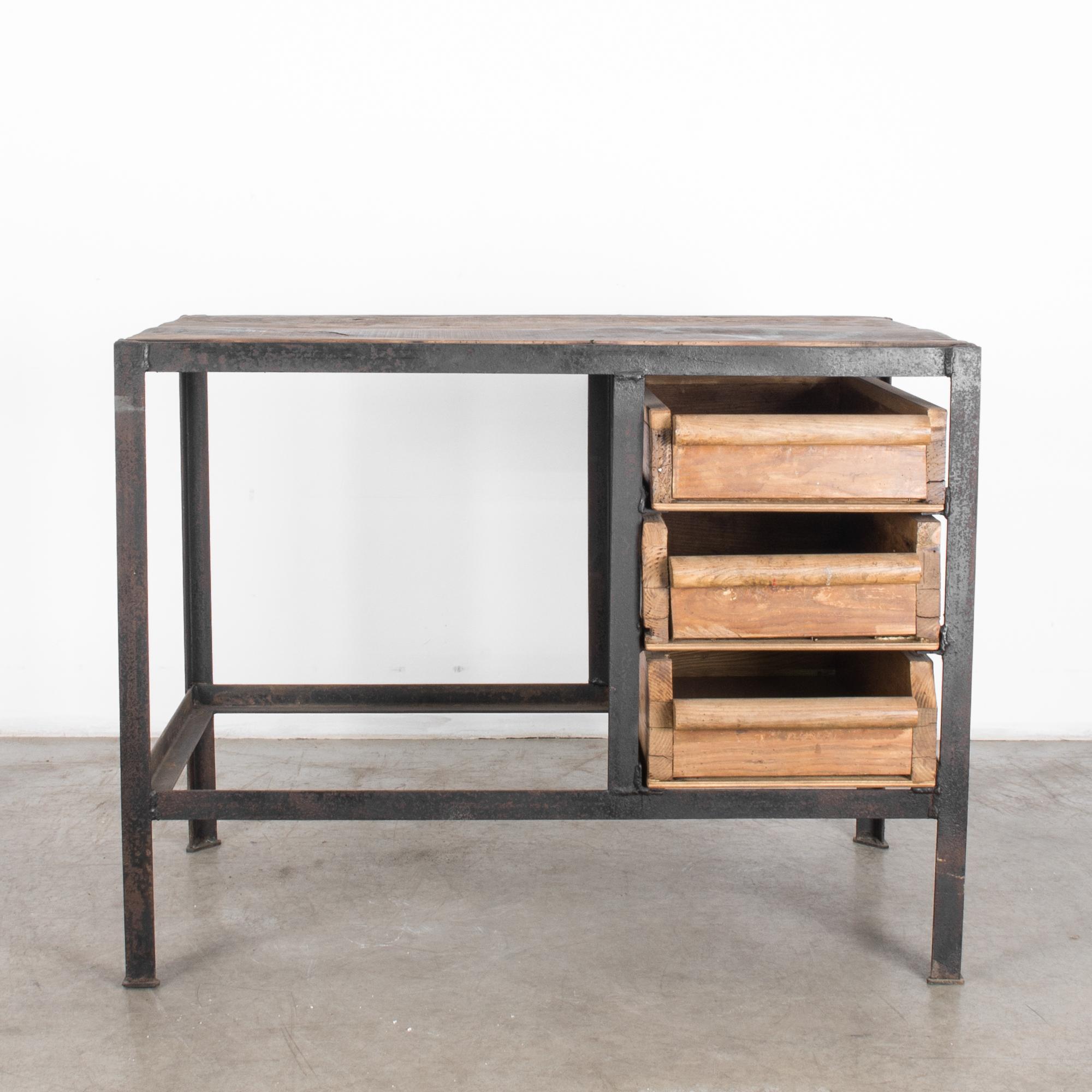 This fully functional worktable was made in France, circa 1920. The beautifully aged, rectangular metal frame has a distinctive industrial appearance and supports three rustic and solid wooden drawers on one side. A cylindrical pull stretches across