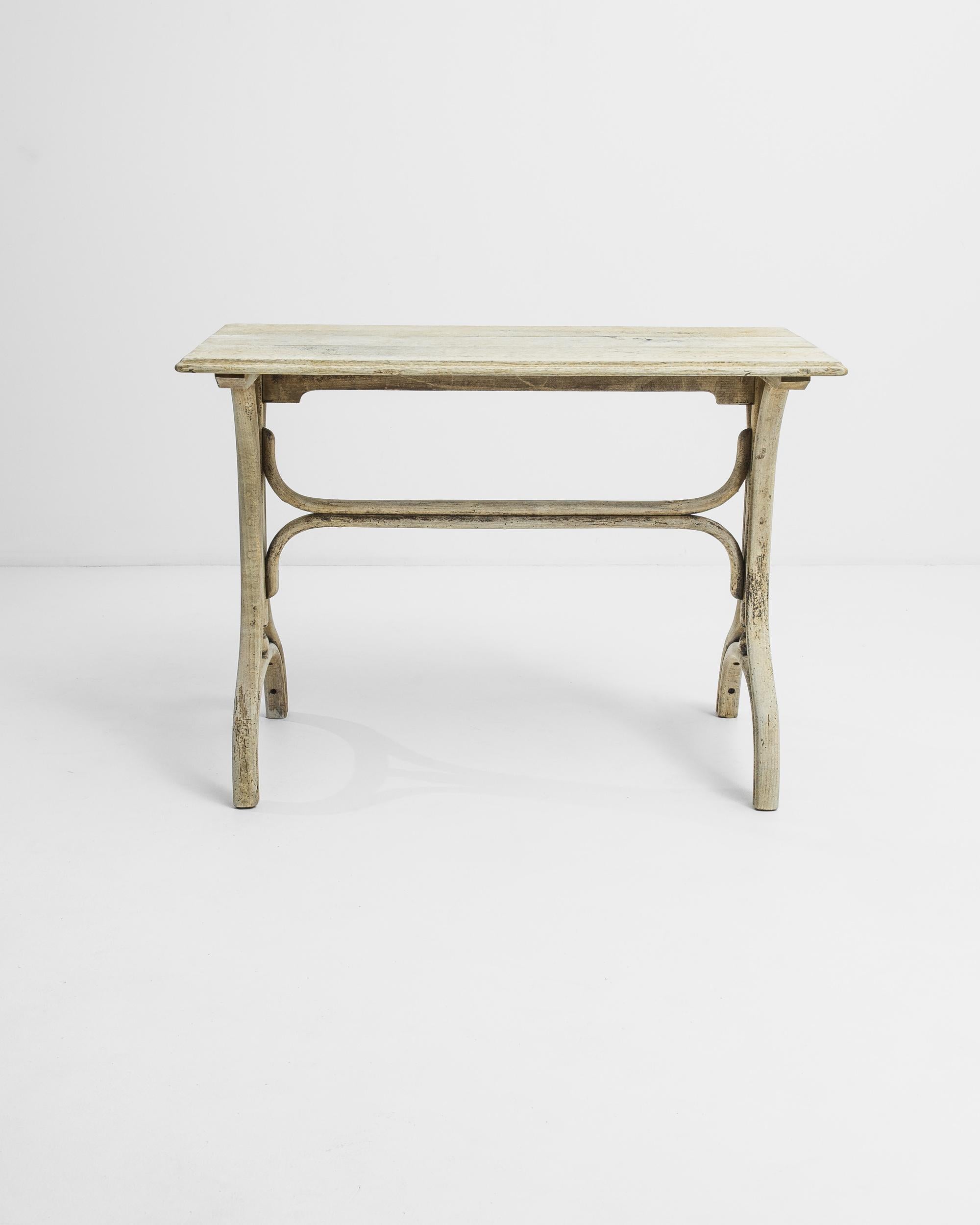 This occasional oak table was made in France circa 1920. The smooth tabletop is raised on the skillfully carved trestle base terminating in eccentric convex feet that playfully follow the smooth outline of the curved stretcher. The characteristic