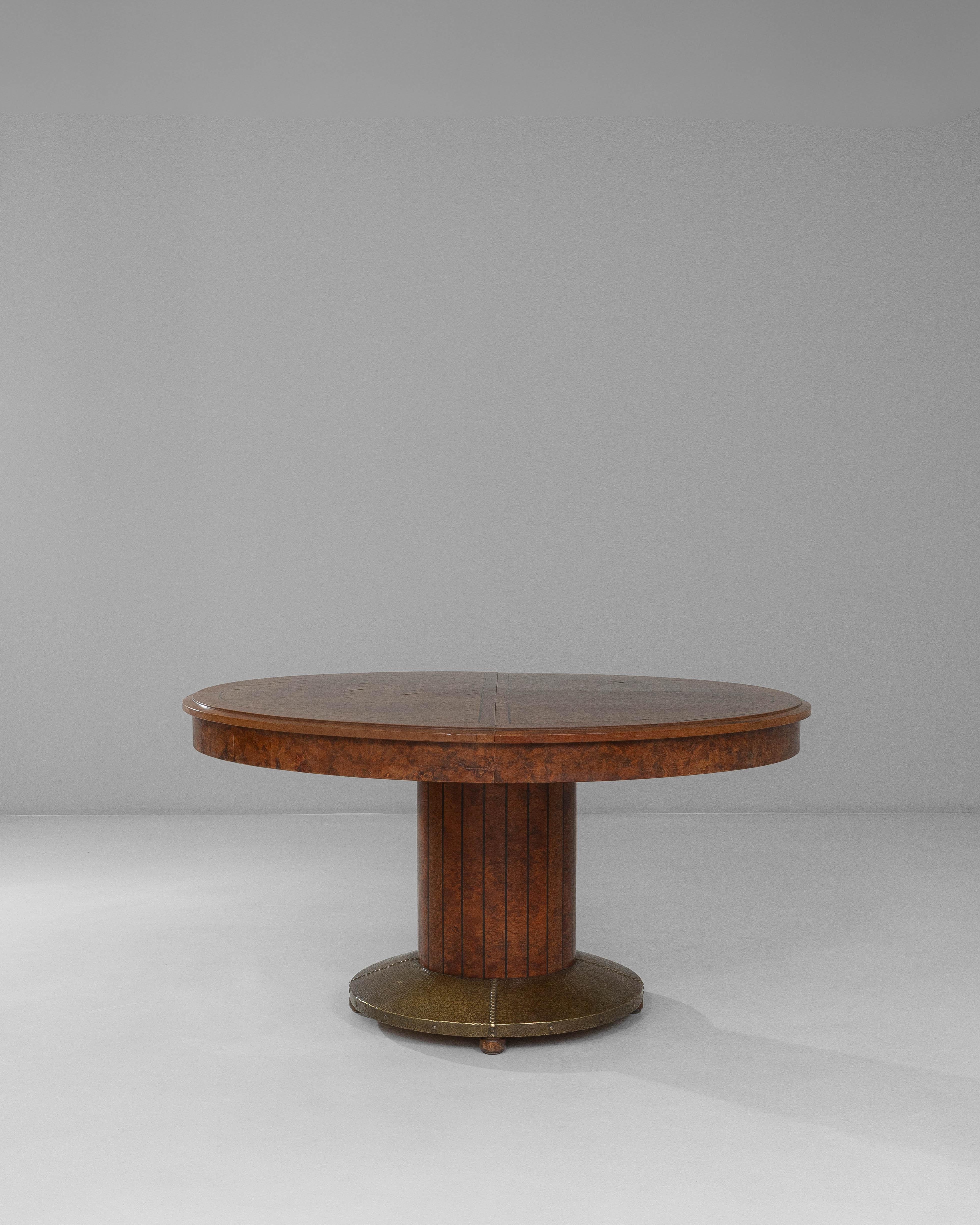 This 1920s French Art Deco dining table showcases an elegant oval silhouette paired with refined craftsmanship characteristic of the period. The richly inlaid top displays beautiful grain movement and subtle geometric detailing, offering both visual