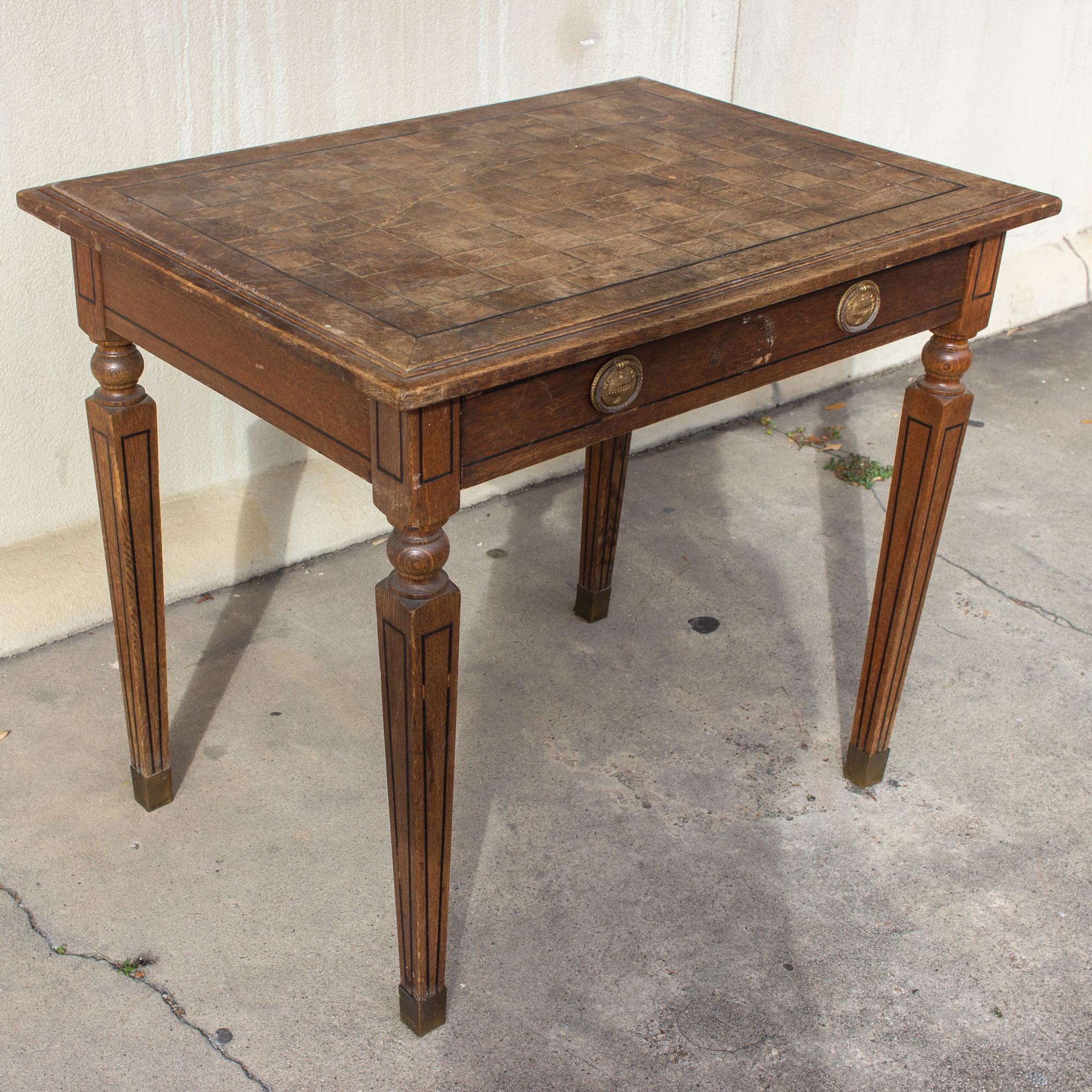 This antique French desk features a beautifully handcrafted parquet top, turned and tapered legs, pinstripe details and brass sleeved feet. It's compact size is ideal for creating a flexible work-space while still offering storage within. The drawer