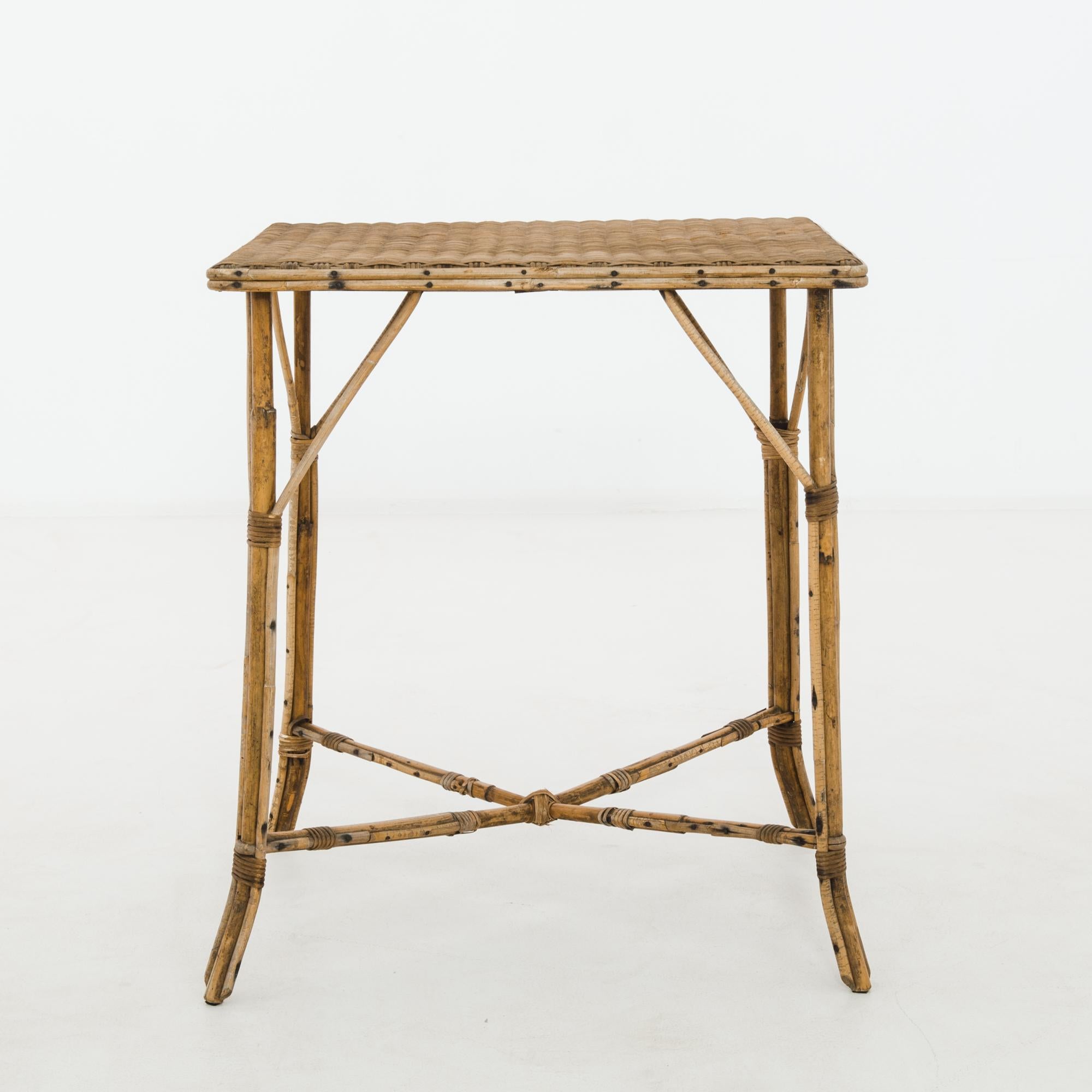 A rattan table from France, produced circa 1920. Bundles of lashed stalks, connected in the middle via x-shaped stretcher, support a tightly woven rattan tabletop in this featherweight table that invokes warm weather climes.