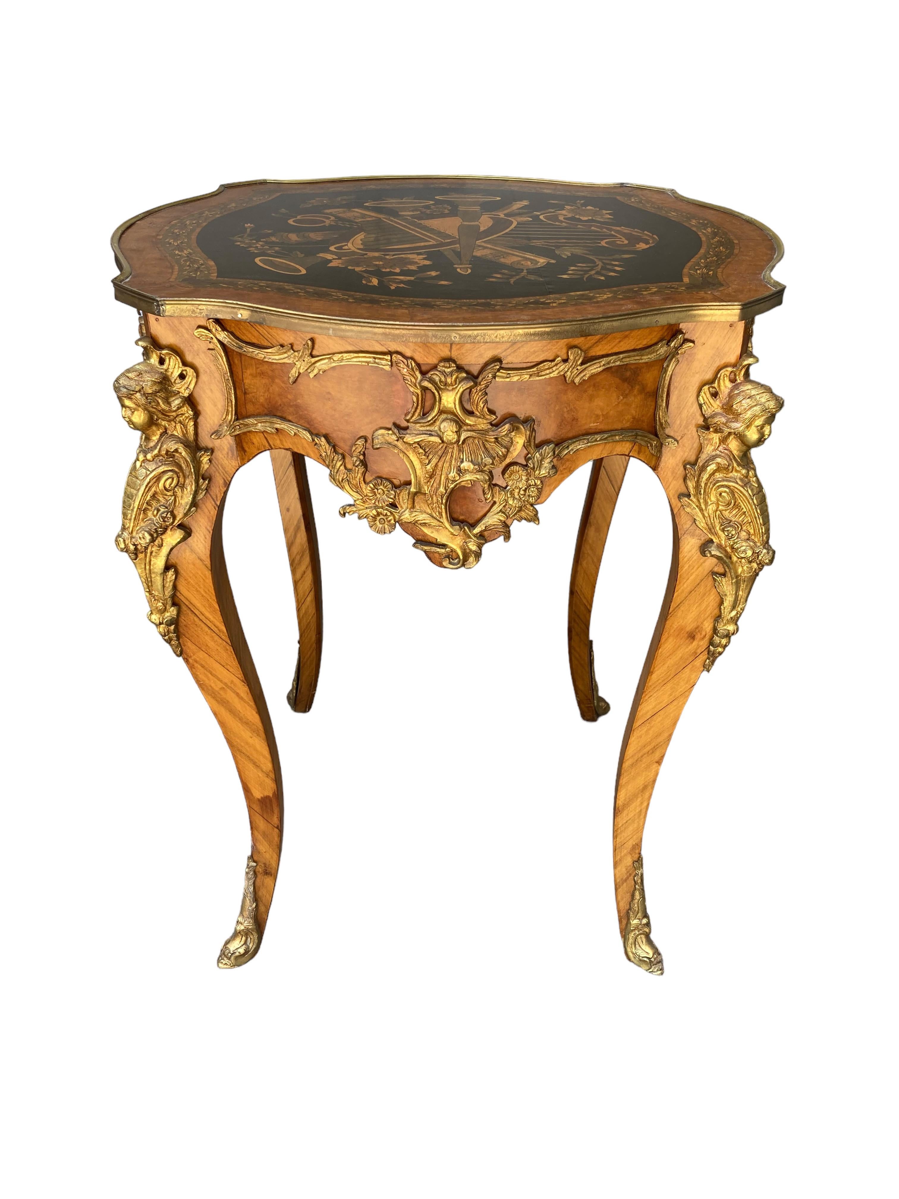 This 1920s Round Hand Painted Ormolu Side Table is a beautiful representation of the French Louis XV Rococo style of furniture. The top of the end table’s art was worked into the detail of the wood and is a musical design. The table measures 31 1/2”