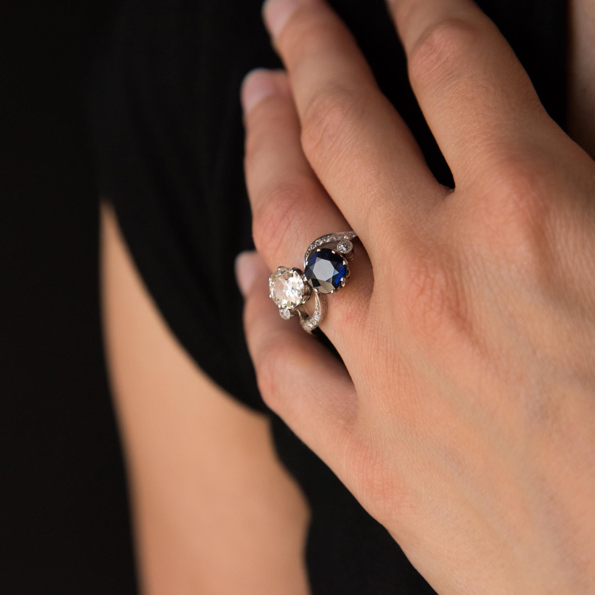 Ring in 18 carat white gold, eagle's head hallmark. 
This splendid antique sapphire and diamond ring features a claw set brilliant antique cut diamond and a round blue sapphire, shouldered by two bezel set diamonds. The top of the ring is
