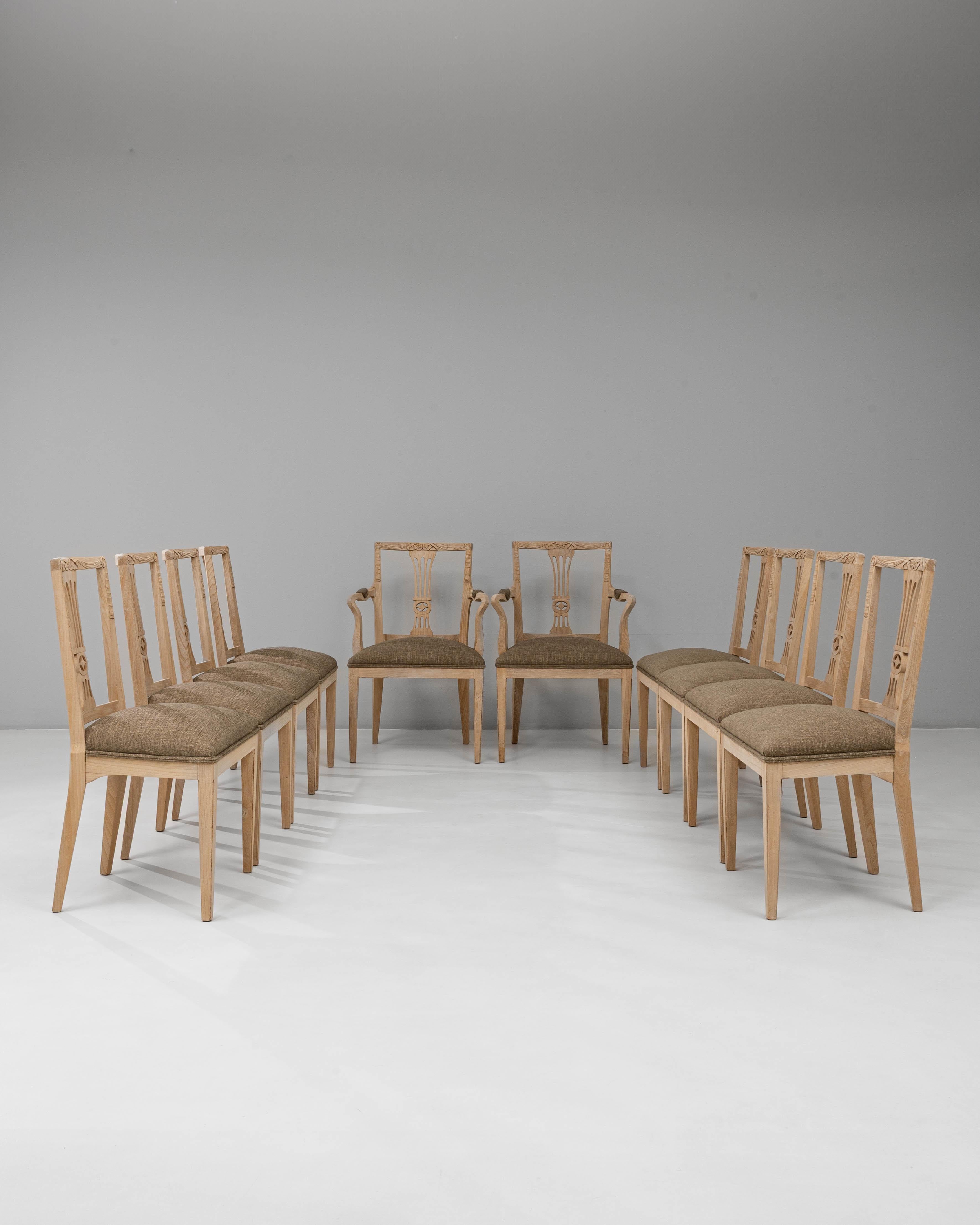 This 1920s French set of 10 oak dining chairs, including two armchairs, reflects refined neoclassical elegance and craftsmanship. Each chair features a hand-carved lyre-shaped back with subtle floral detailing, showcasing the balance and symmetry