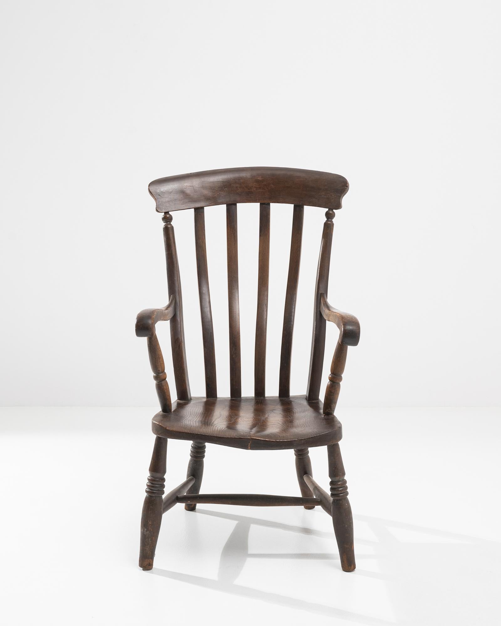 Tapering and waving spindles above sloping arm rails and lathed legs give this chair a poetic character. Made in France circa 1920, the wood has retained its original finish. The right-angled, upright seat is softened with an ergonomic contour and
