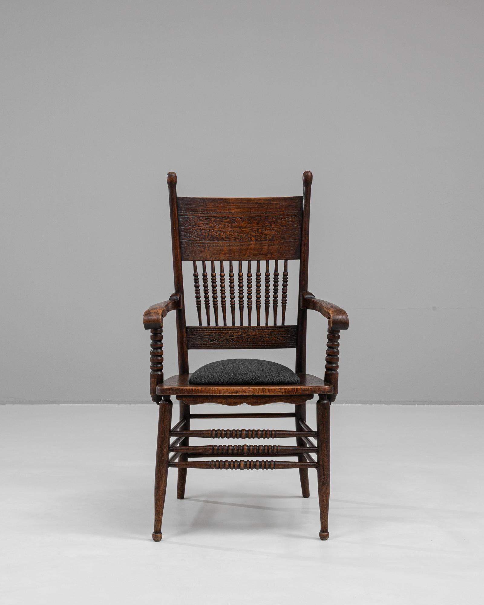This elegant 1920s French wooden armchair embodies classic craftsmanship with its detailed turned spindles and hand-carved oak structure. The chair’s high backrest and gracefully curved armrests showcase intricate woodwork, giving it both visual