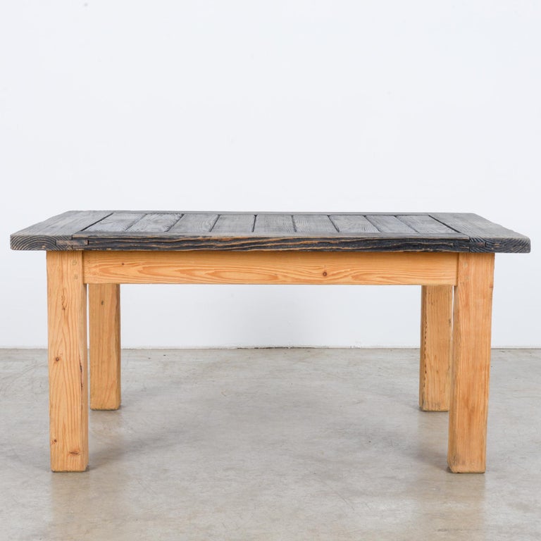 This wooden coffee table with a simple, geometric form was made in France, circa 1920. Rows of wooden planks, framed on the sides, form the tabletop. It is stained black, setting off the bright tones of the angular and sturdy posts.