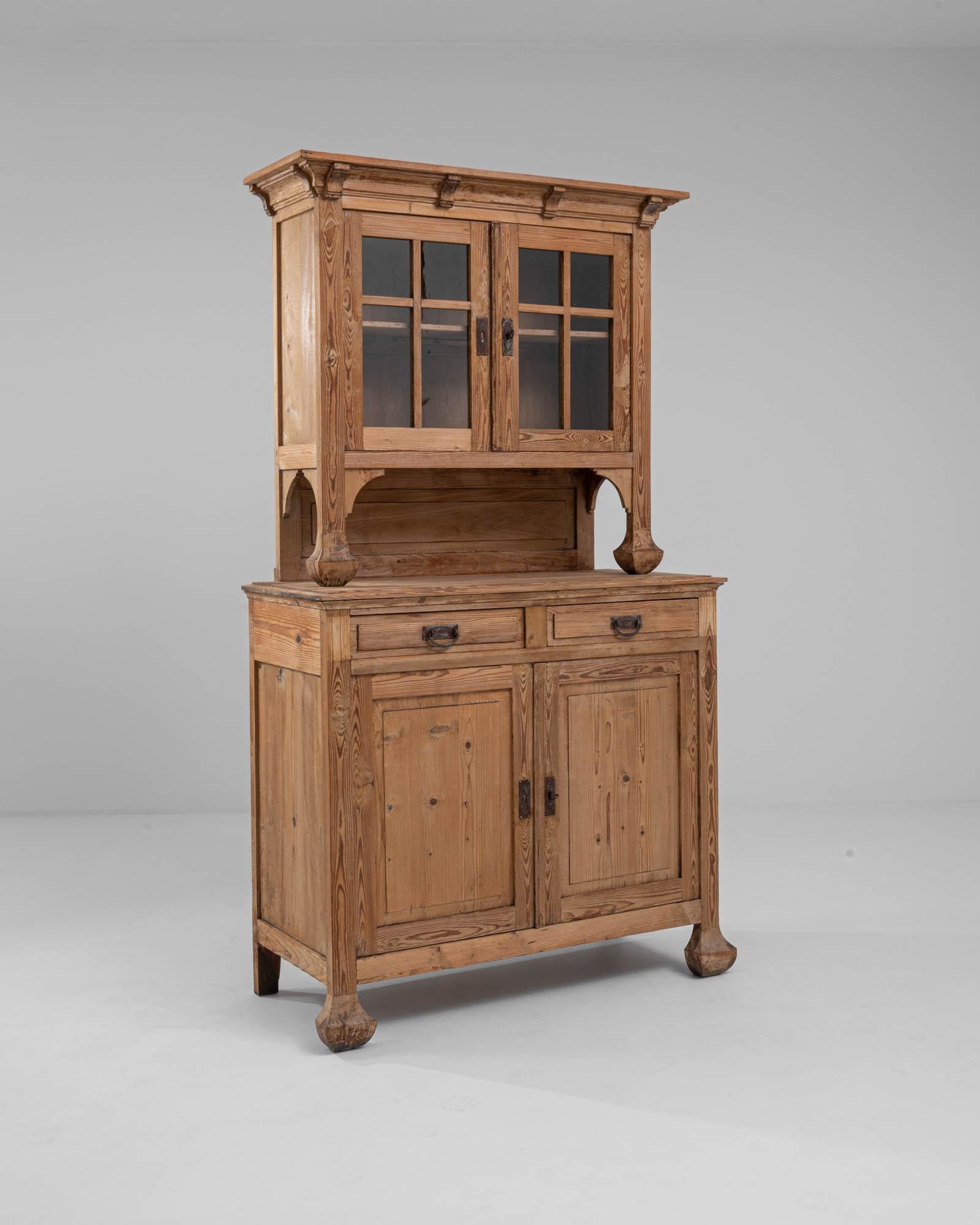 A wooden vitrine made in 1920s France. The vitrine is composed atop a lower cabinet with two doors and two drawers, and the display case resting above with a charming glazed frame. The bulbous, tapered feet along with carved corbels elevate the warm