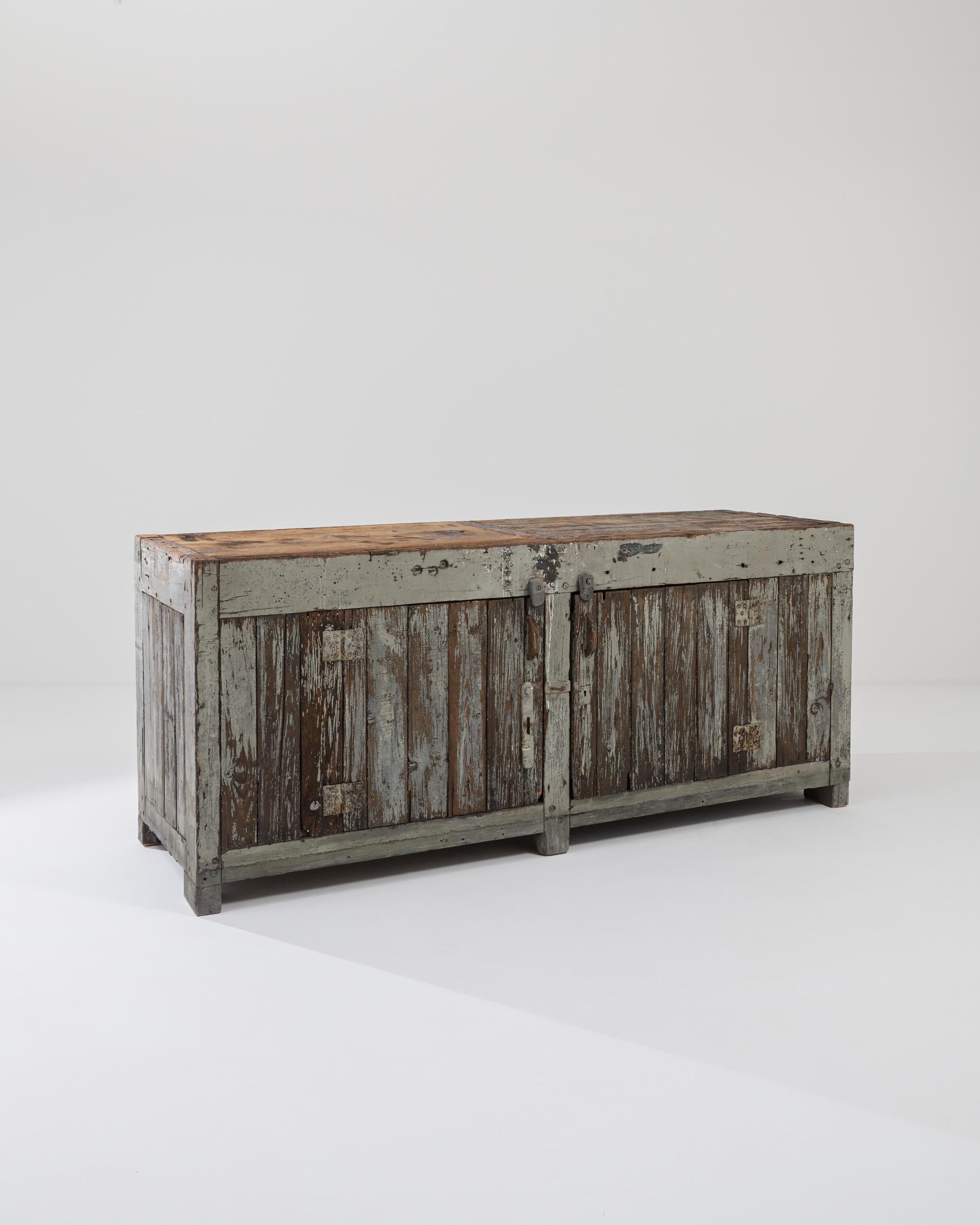 Sourced in France, this wooden work bench was made circa 1920. Coated in a coat of gray paint on the front and black on the back, both of which have slowly ebbed away due to the effects of time, rendering a stunning patina that indicates that this