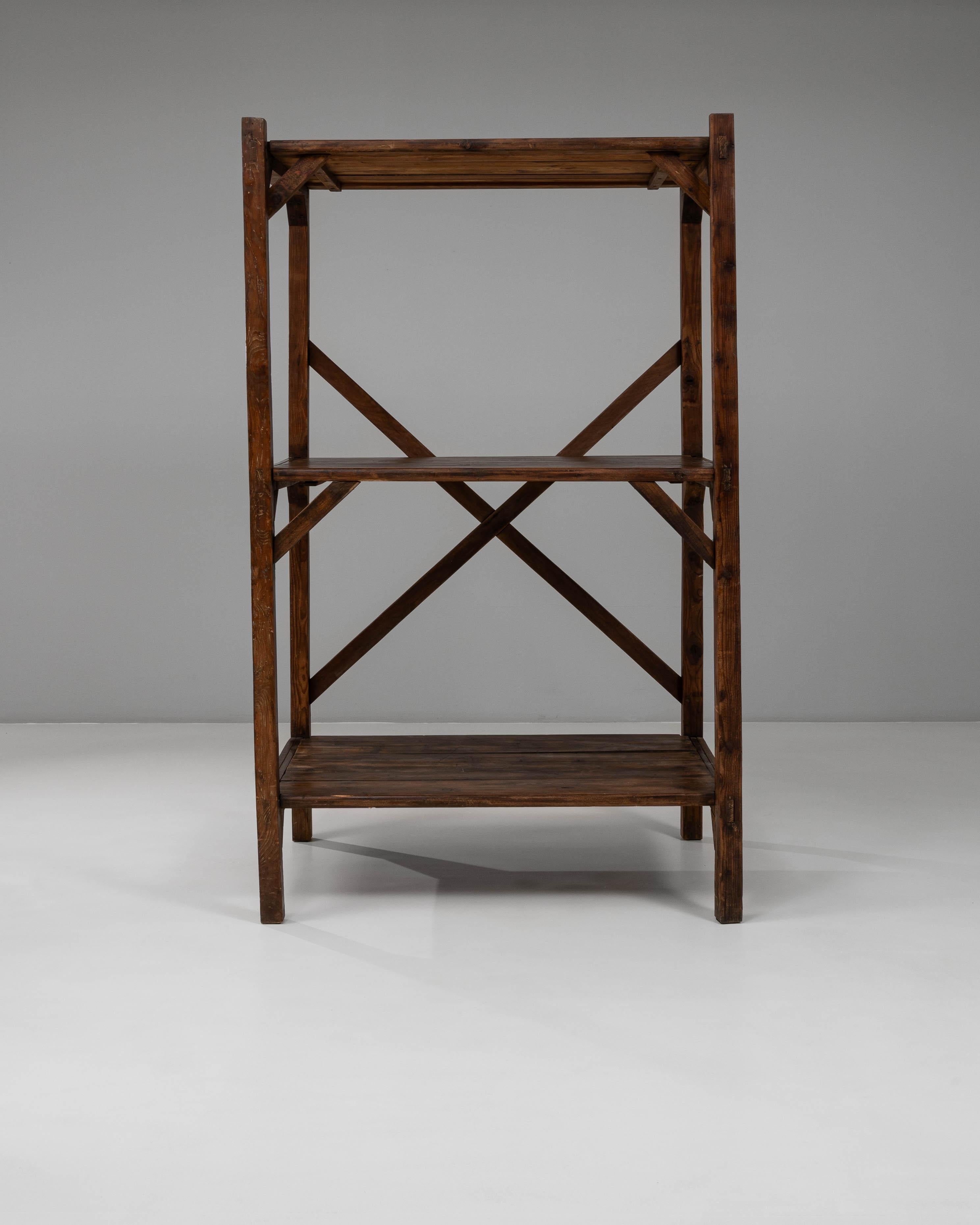 Questo scaffale francese a X degli anni '20 offre una presenza funzionale e architettonica definita dalle sue linee pulite e dalla sua struttura robusta. Realizzato in legno dai toni ricchi e con una finitura naturalmente invecchiata, il pezzo