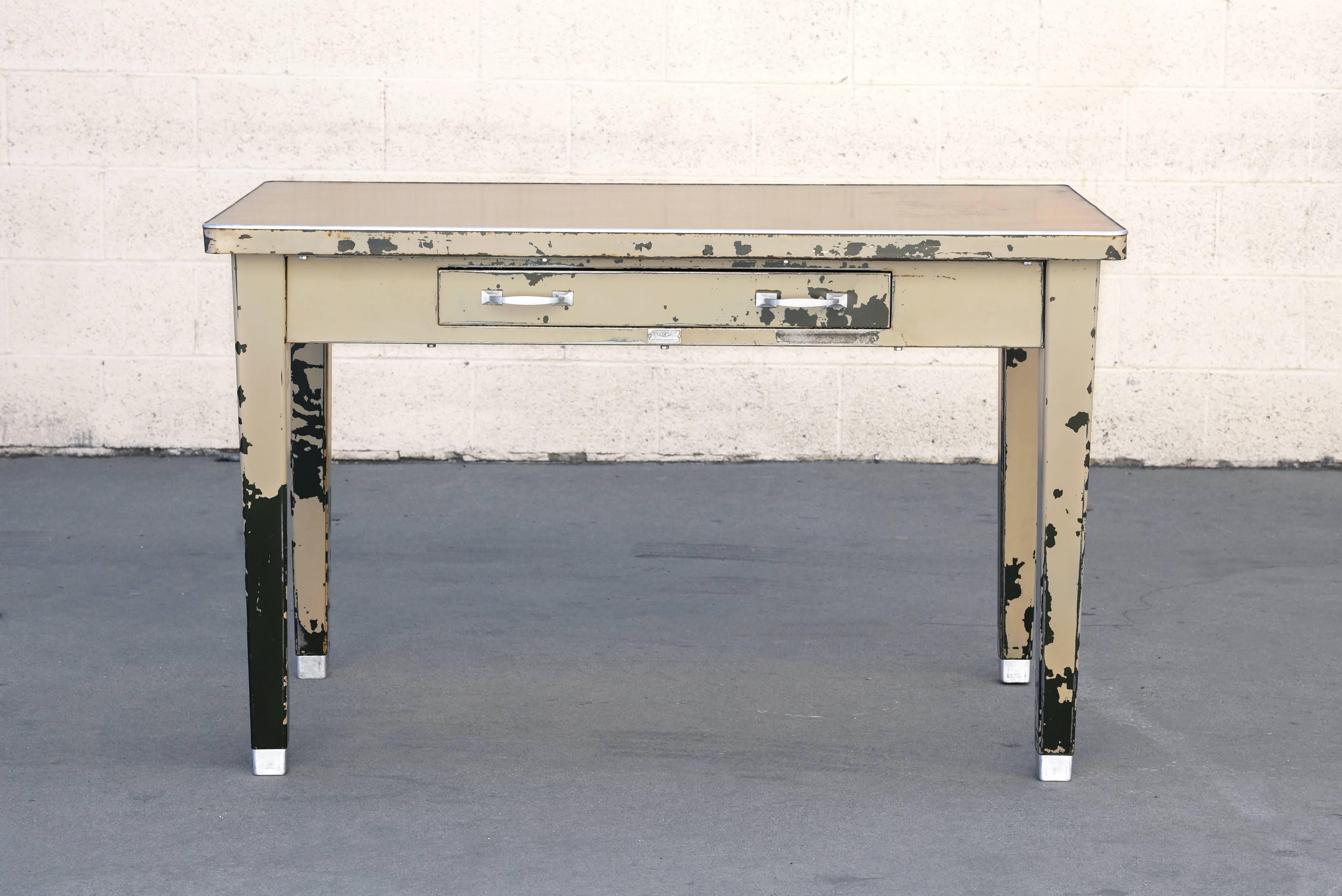 Industrial era four-legged tanker table by General Fireproofing Co., with a characteristic weathered patina. We accentuated the finish and added a light satin clear coat. All original aluminum hardware polished to a shine. Features single utility