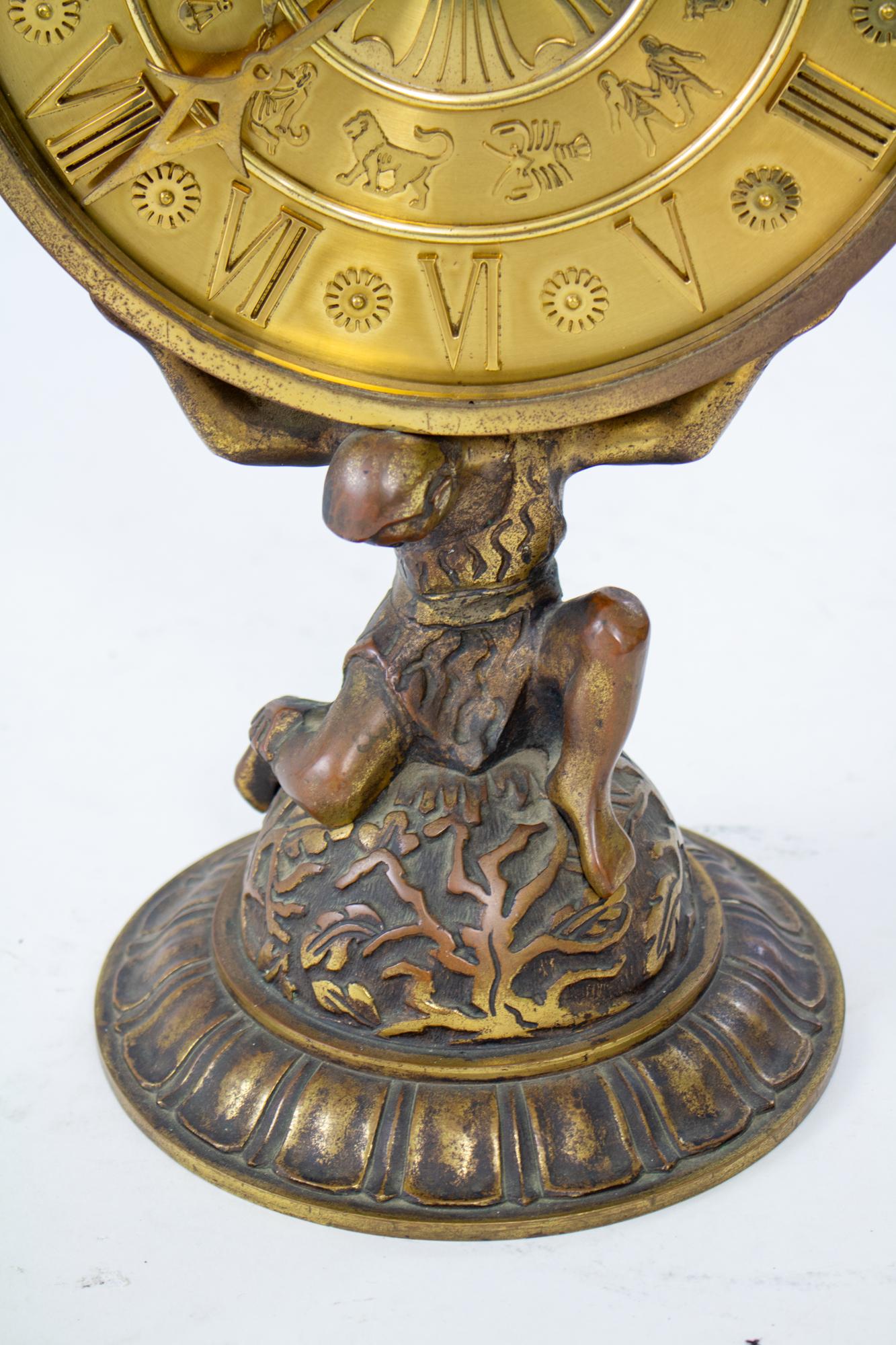 1920’s gilt bronze ImHof Atlas and zodiac desk clock. A statement piece of a desk clock. Atlas holds on his shoulders the round face with large roman numerals and the symbols of the zodiac. The base is a worn gilt bronze and the face is bright gold.
