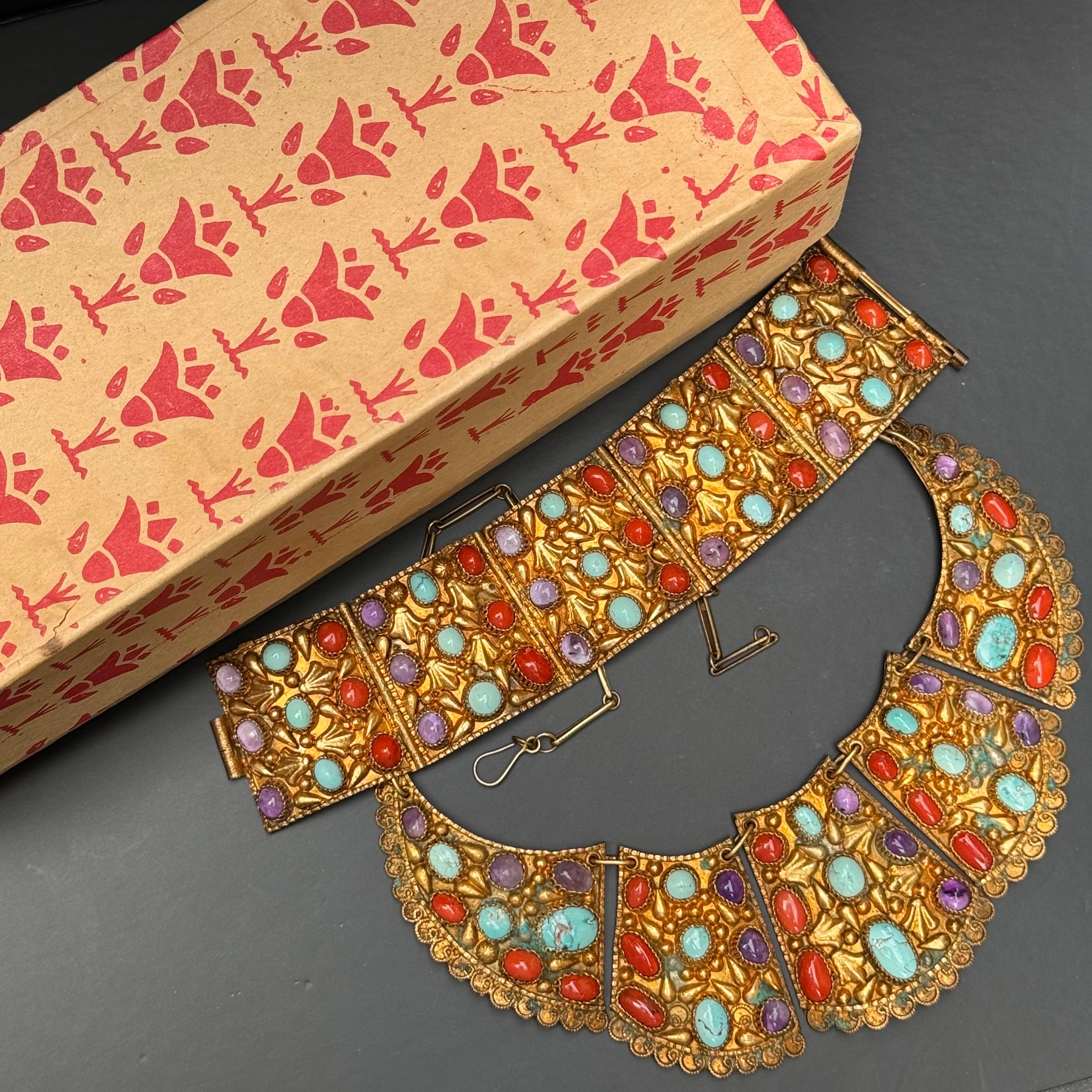 Step into the opulence of the Art Deco era with this exquisite Egyptian Revival bib necklace and matching bracelet with original box . Crafted with meticulous detail, it features a lavish blend of materials: amethyst, coral, and turquoise stones set