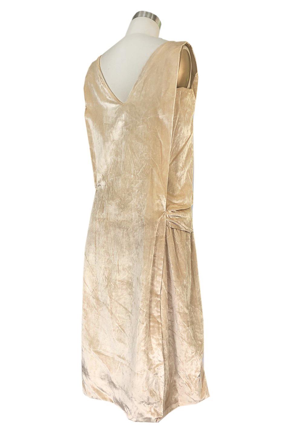 This gorgeous twenties dress combines a rich, golden tone ivory silk velvet with an inset panel of silk chiffon in the same rich color. The front panel where the silk chiffon is inlaid, has been heavily embellished with beads and faux pearls. The