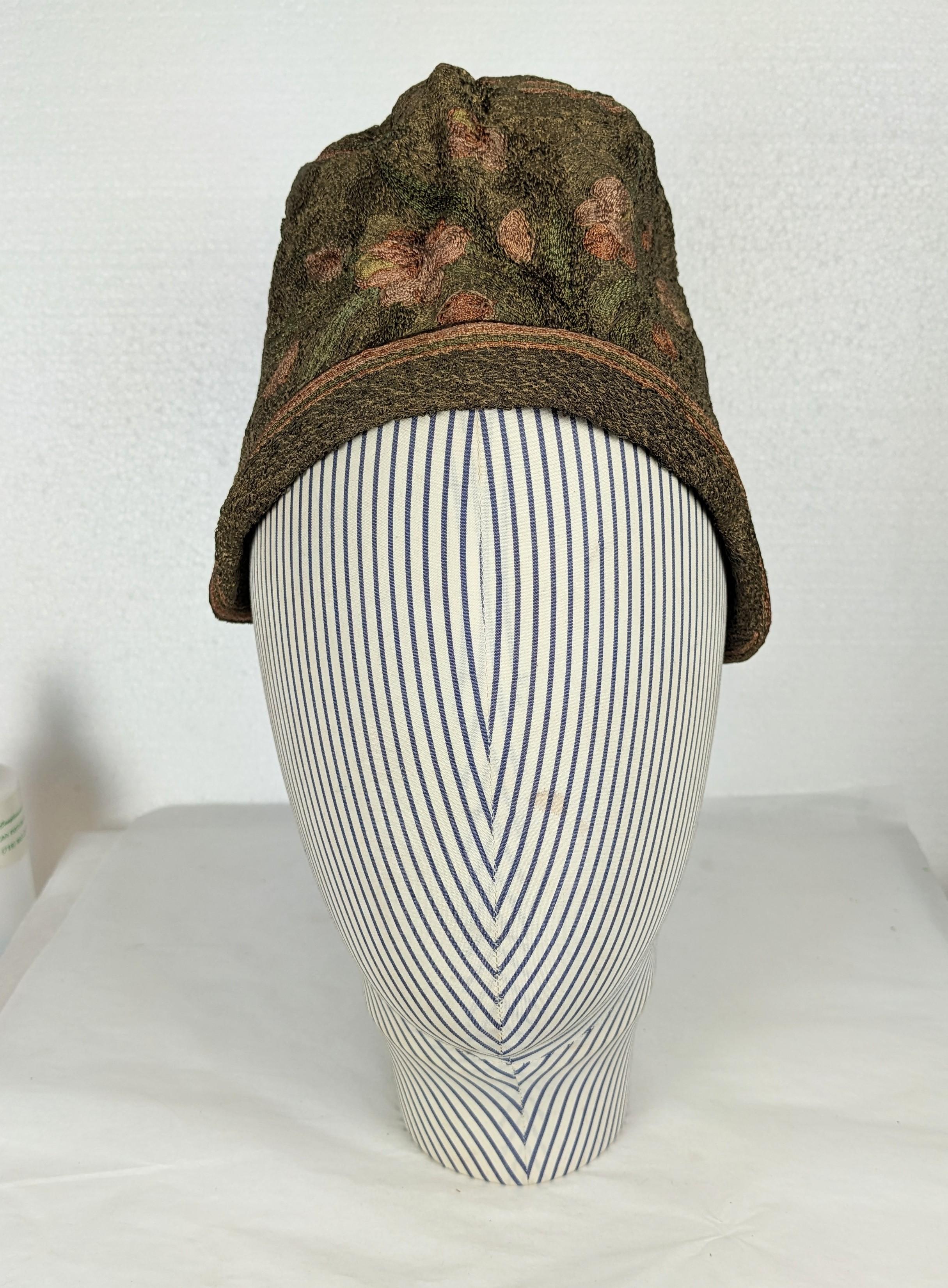 1920's Gold Lame and Needlepoint Cloche Hat. Completely hand embroidered with needlepoint flower motifs on a ground of gold lame bullion metal threads with brown velvet trim. Lined in silk taffeta. 1920's France. Small size. Height 4.5
