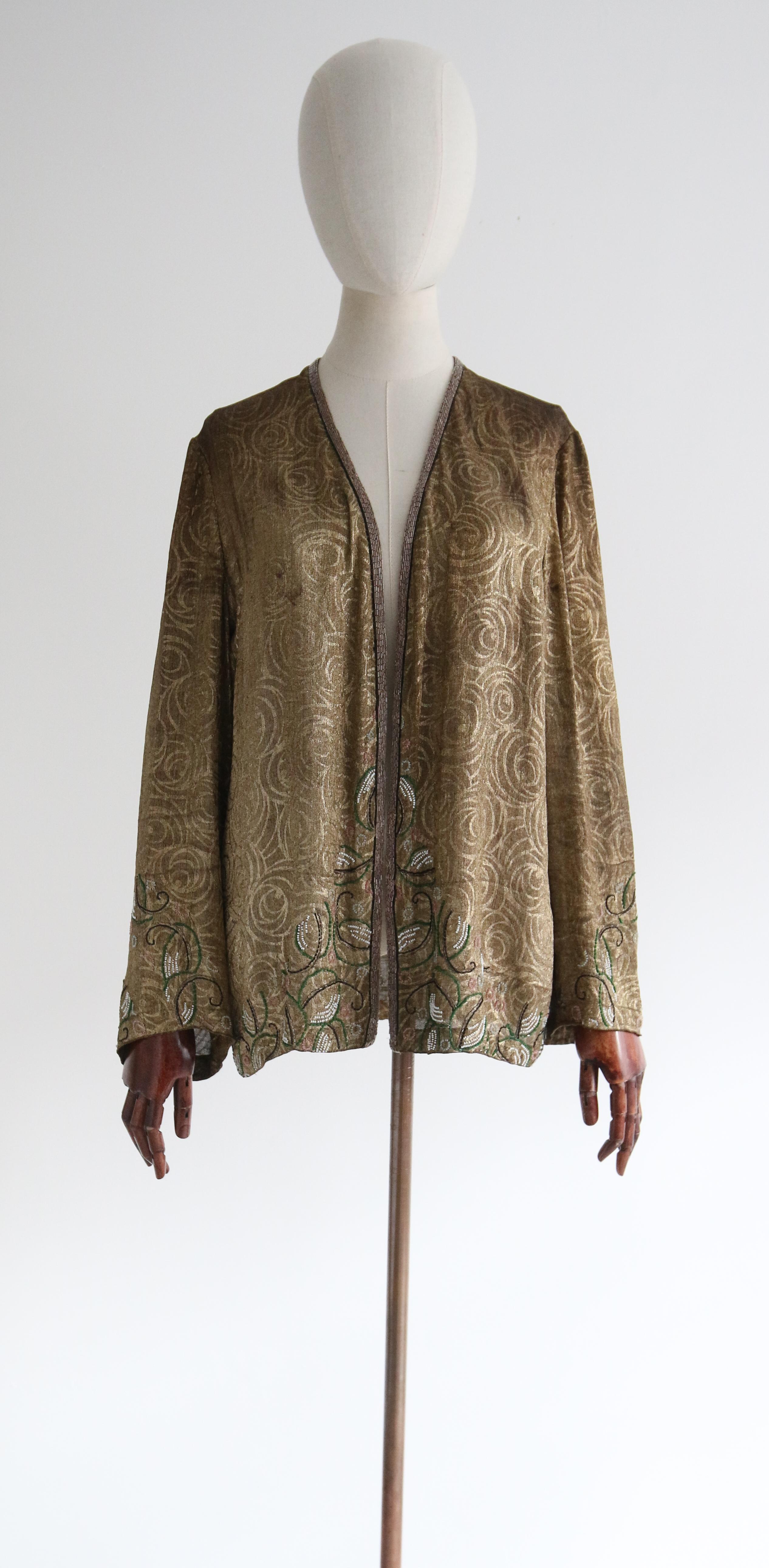 Full of opulent original details, this beautiful 1920's embellished jacket on a swirling gold lamé base is just the piece to add a touch of elegance to your wardrobe.  

The open neckline is set off by an edged to edge cut, fully embellished with a