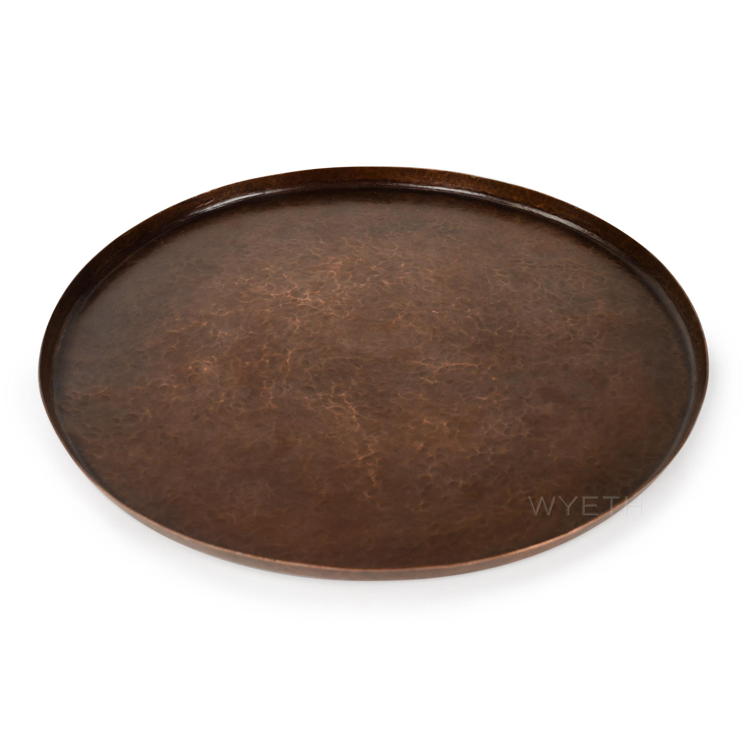 An elegant platter / tray hand forged in hammered copper with a thin upturned rim.