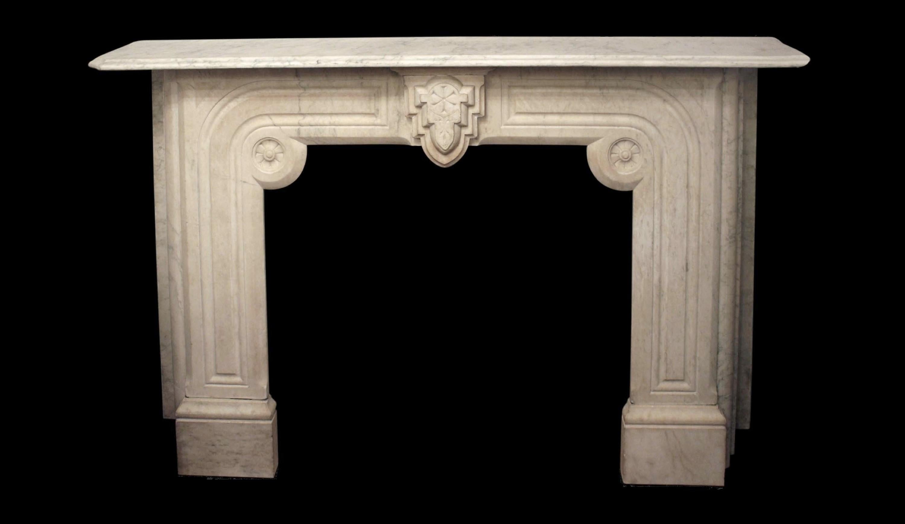 Dating back to the 1920s, this off-white marble mantel showcases elegant gray veining, accompanied by intricate carved geometric patterns interwoven with delicate foliate motifs. The presence of these geometric details renders it a fitting choice