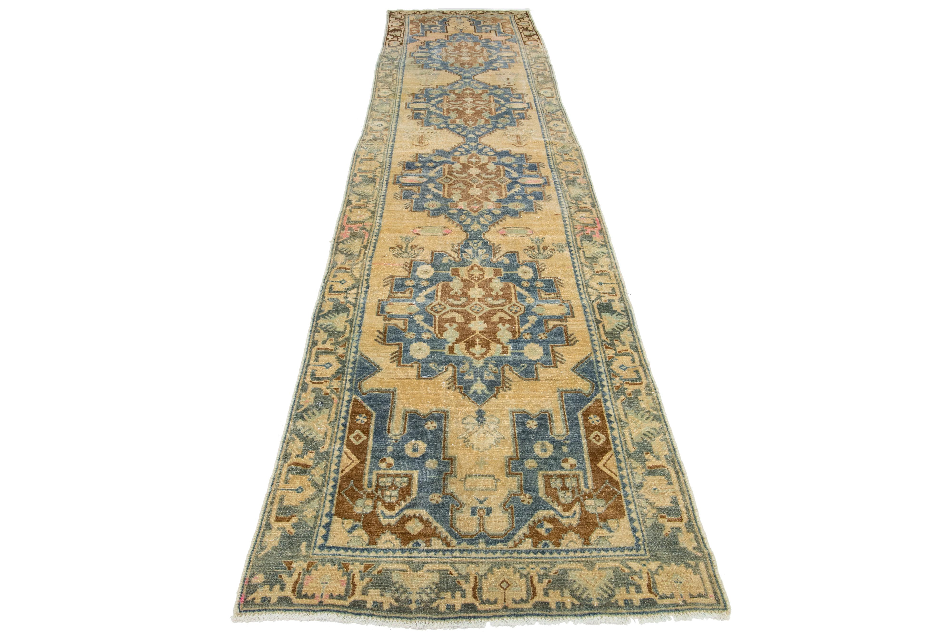 This beautiful 20th-century Heriz hand-knotted wool runner has a light brown color field. This Piece has blue and pink accents in a gorgeous tribal design.

This rug measures 3'5