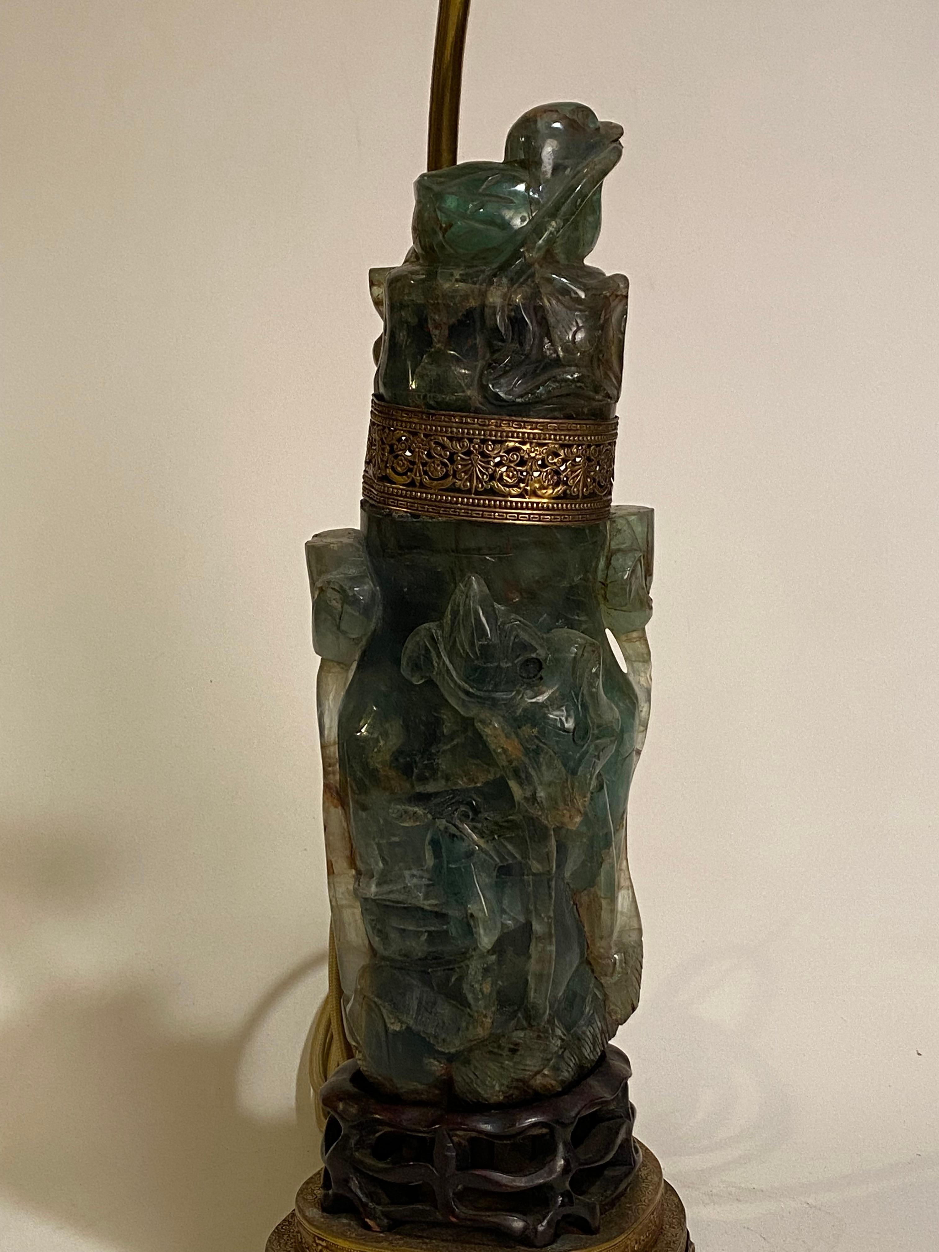 Asiatische Tischlampe mit geschnitztem Vogel aus Jade und Nephrit. Ca. 1920. Der innere Teil leuchtet getrennt von den beiden oberen Lichtern. Durchbrochener Sockel aus geschnitztem Palisanderholz, der mit einem filigranen Fuß aus Messing endet.