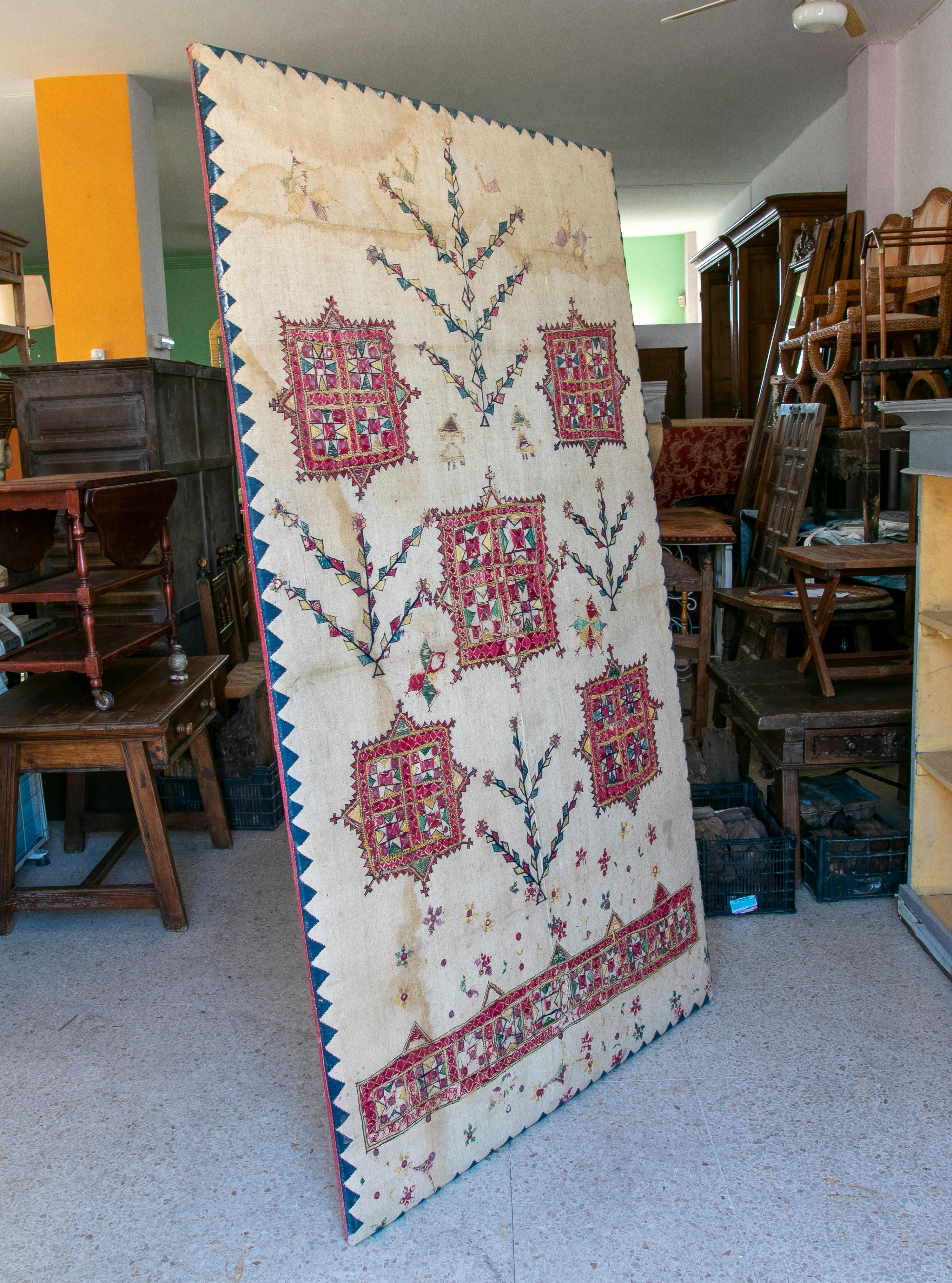 Indischer handbestickter Seidenteppich aus den 1920er Jahren mit ethnischen geometrischen Mustern, auf einem Holzrahmen, bereit zum Aufhängen an der Wand.