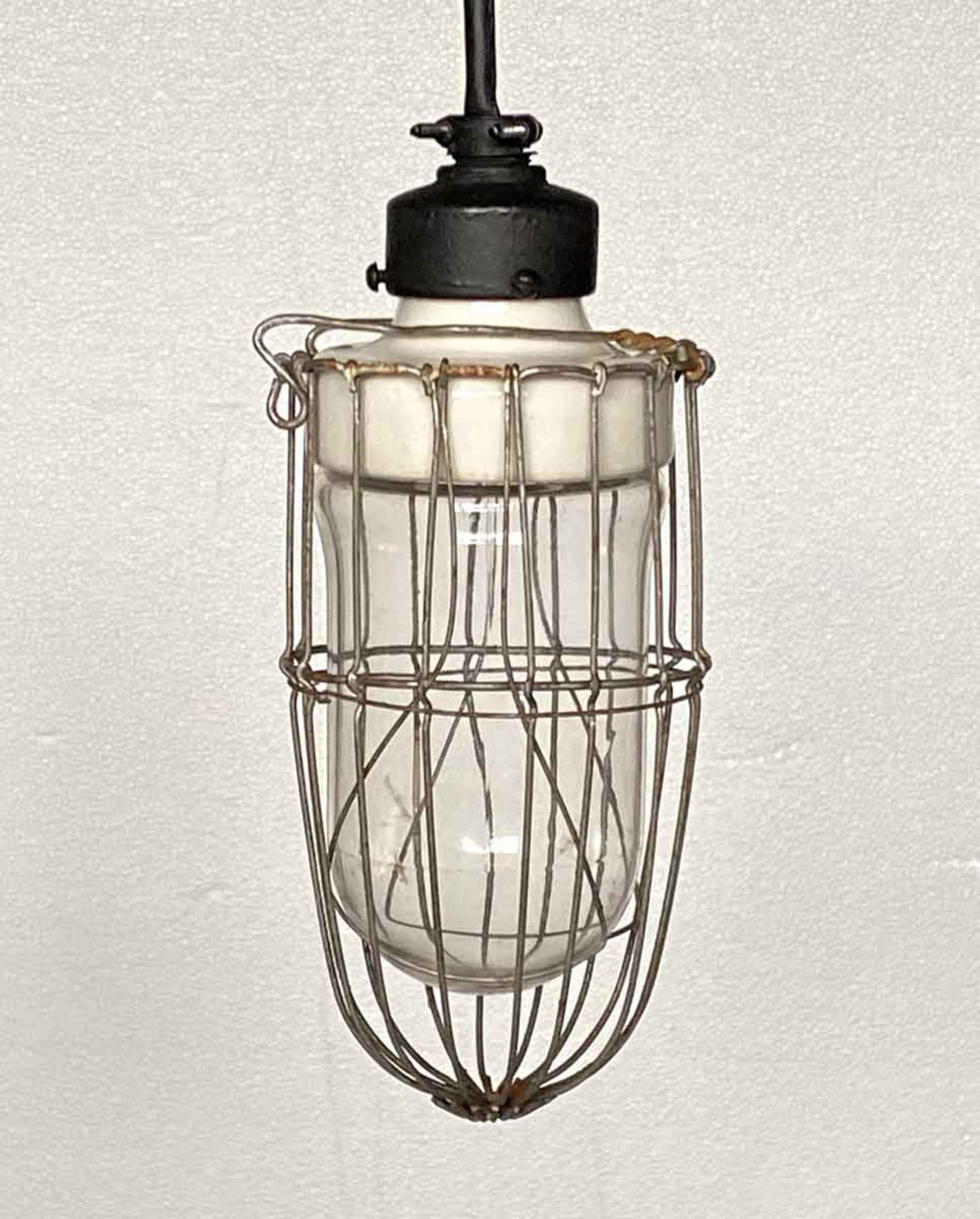 Industrial cage light with thick original porcelain fixture, circa 1920. This has been recently rewired with a long cord and matching black canopy. Please specify the overall drop that is needed upon purchasing. Please note, this item is located in