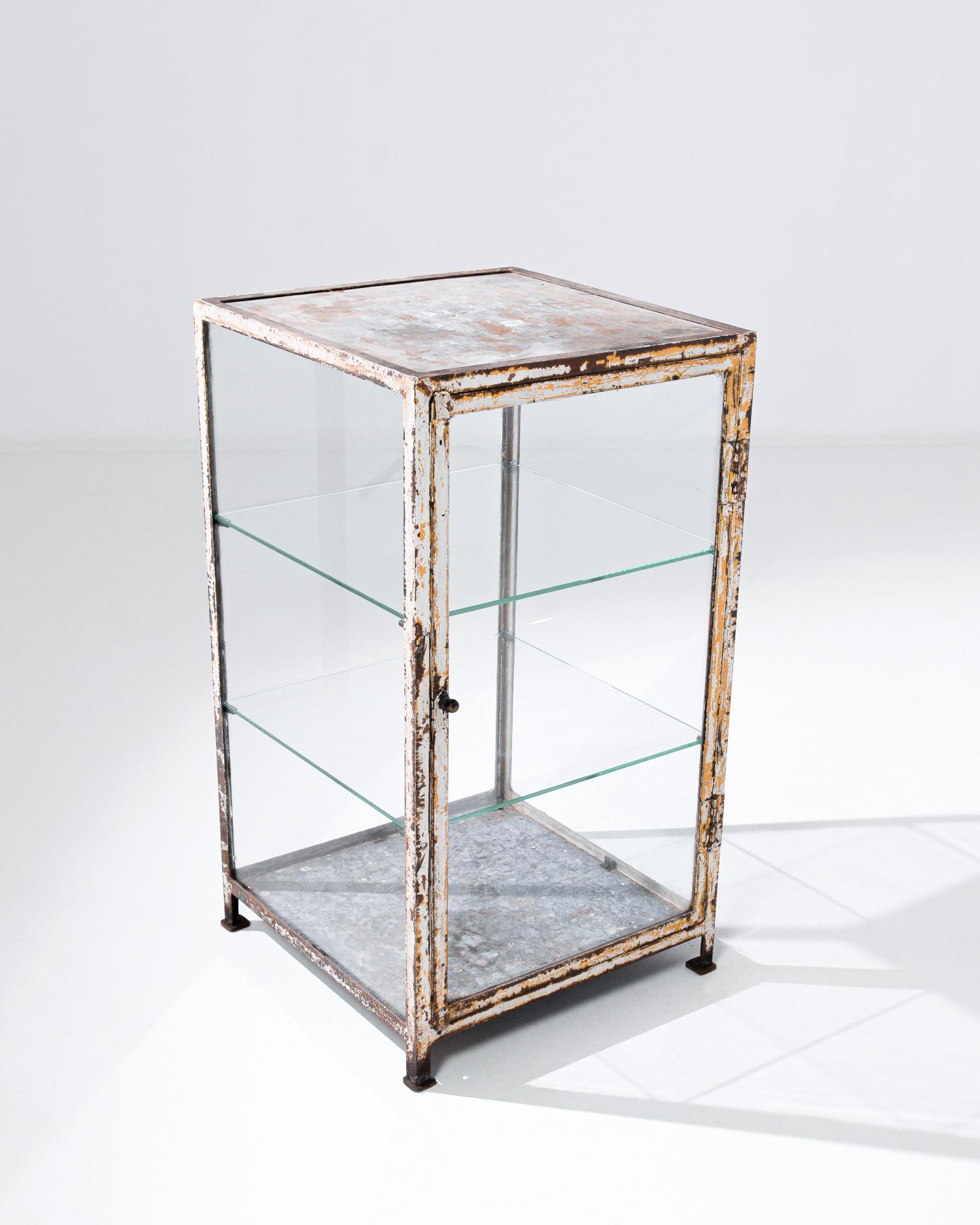 Made in France in the beginning of the 20th century, this two foot six inch tall, one and a half foot wide vitrine features glass walls outlined by the coarse metal frame. Two transparent glass shelves add an extra dimensional feel. Enlivened with