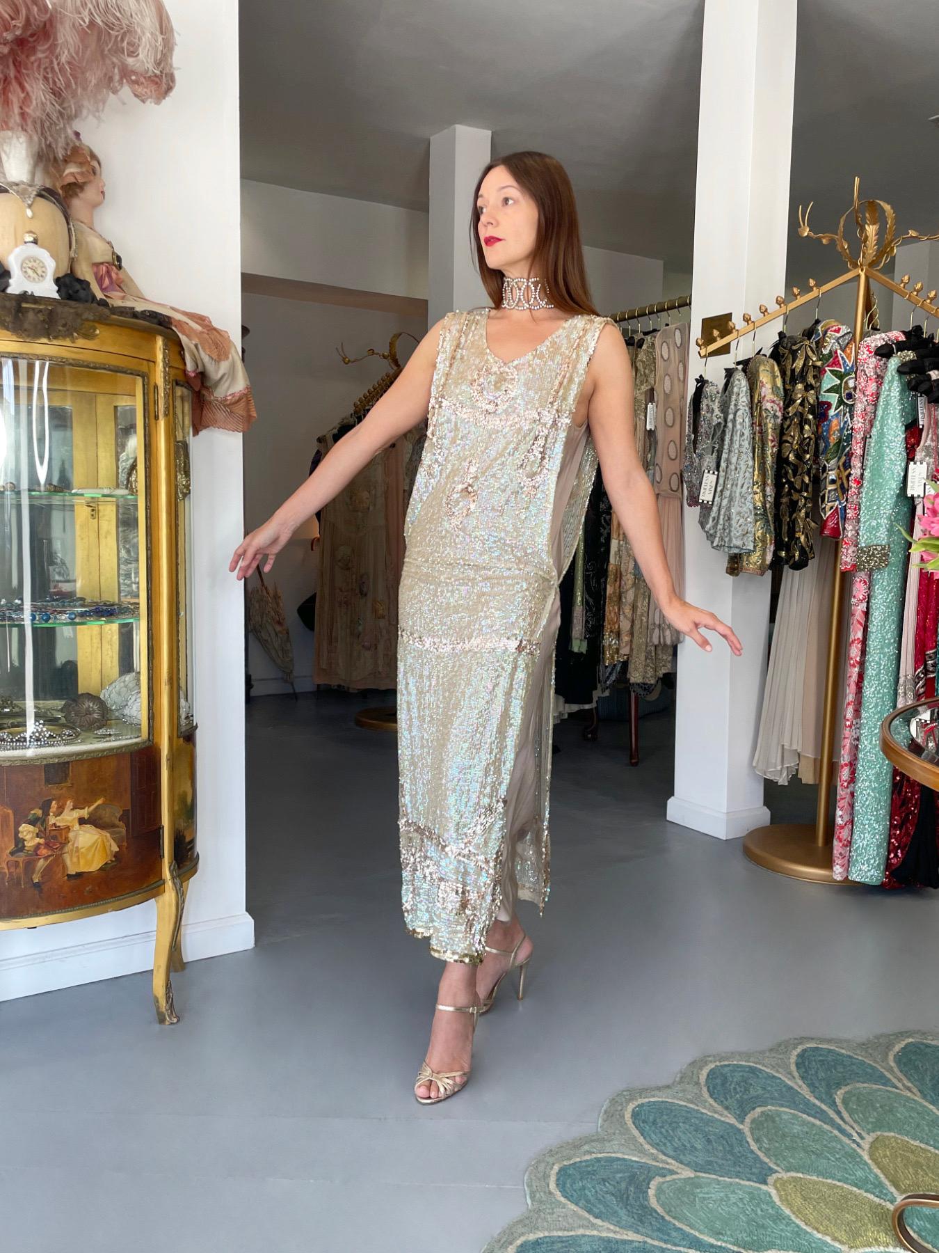 We are so thrilled to offer this extraordinarily beautiful and exceptionally rare French sequin sheer-net tabard flapper dance dress dating back to the mid 1920's. Iridescent glossy ivory sequins are mixed with metallic gold sequins in the most