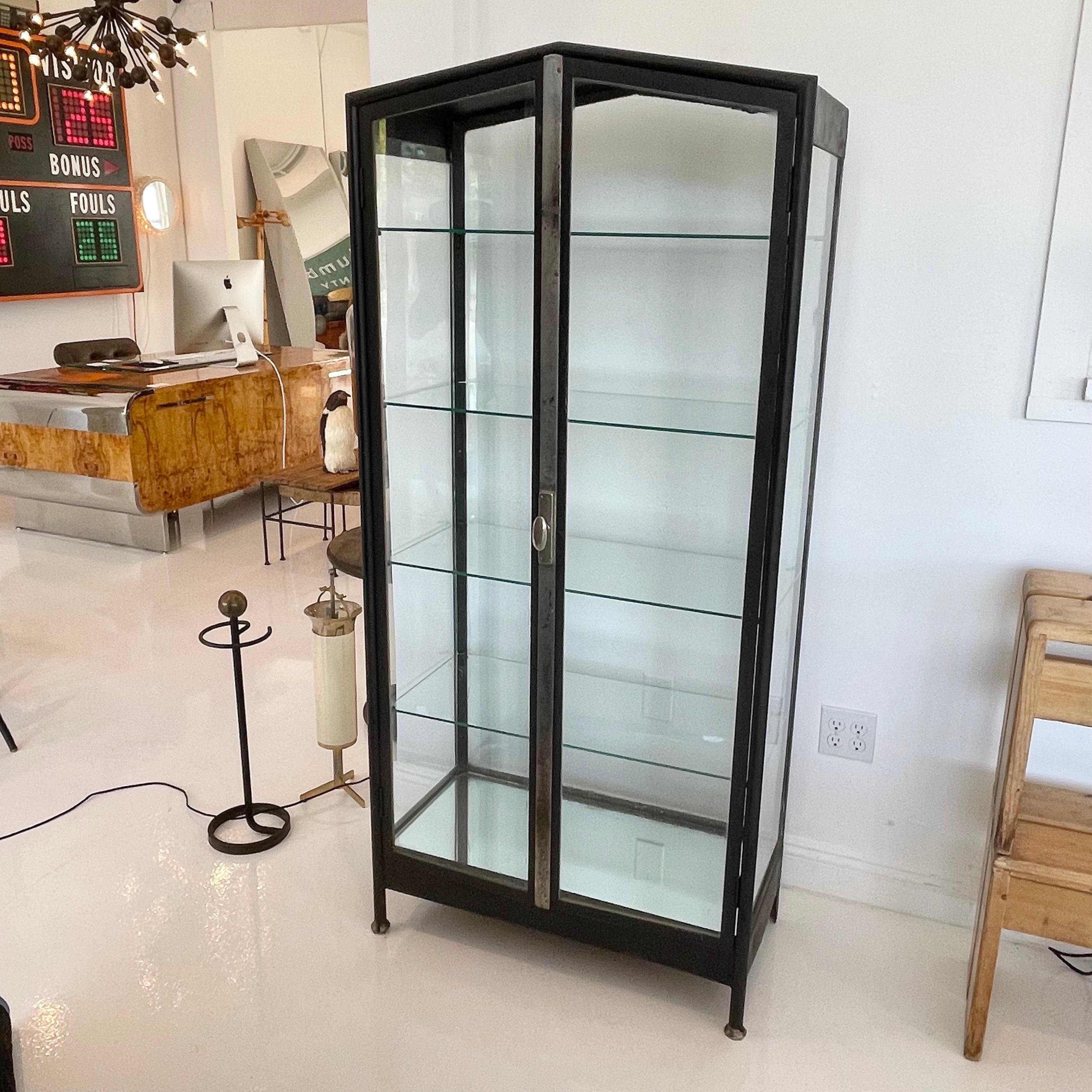 Classic iron and glass vitrine from Argentina, made in the 1920s. Two doors open wide. 4 glass shelves. Glass on all sides. Mirrored bottom. Gorgeous display cabinet. Great vintage condition.