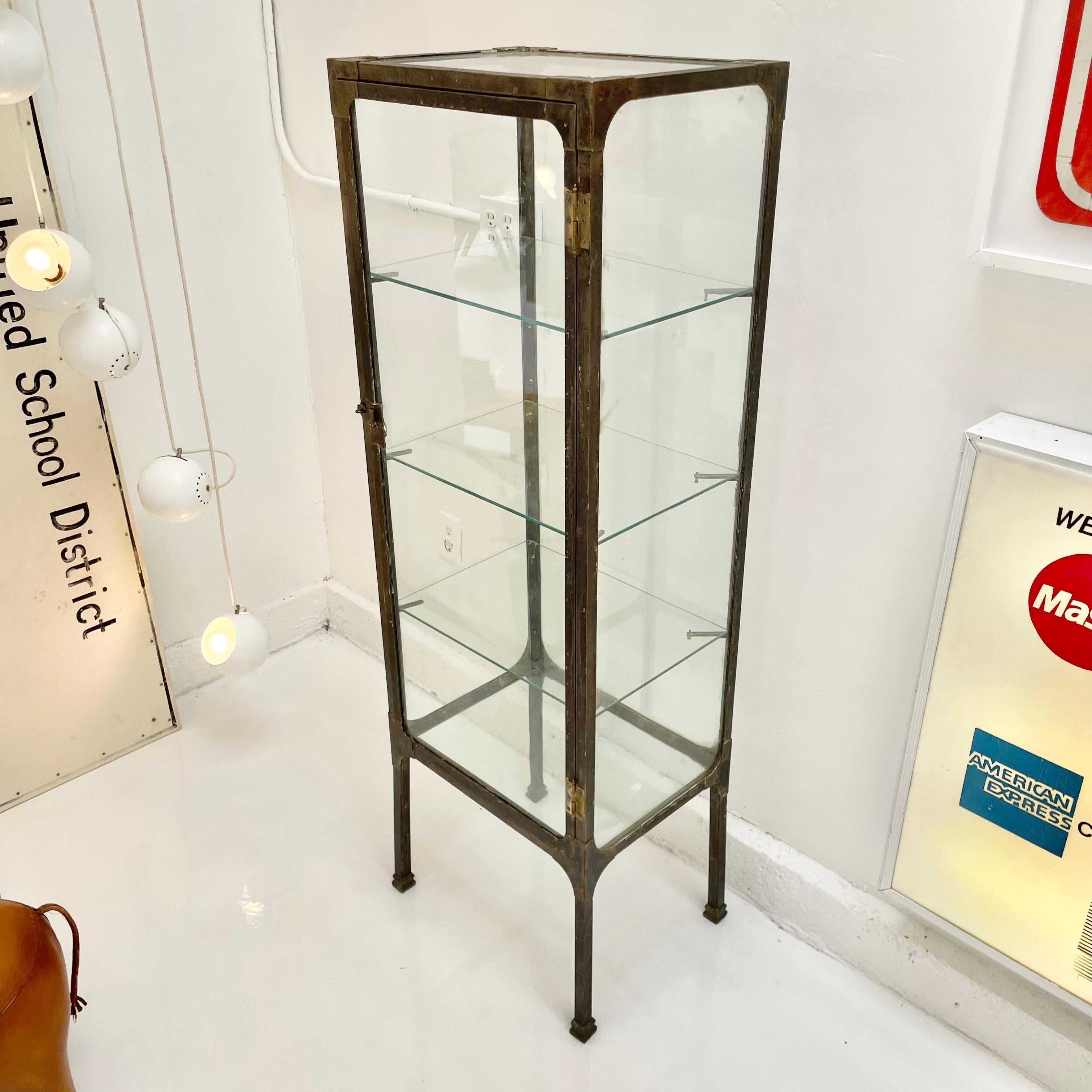 Slender Art Deco vitrine made in the 1920s in Buenos Aires, Argentina. Rectangular frame sitting atop tapered legs. Original glass frame with rare glass top and bottom. Three glass shelves. Vintage clasp sold with vintage padlock. Fantastic display