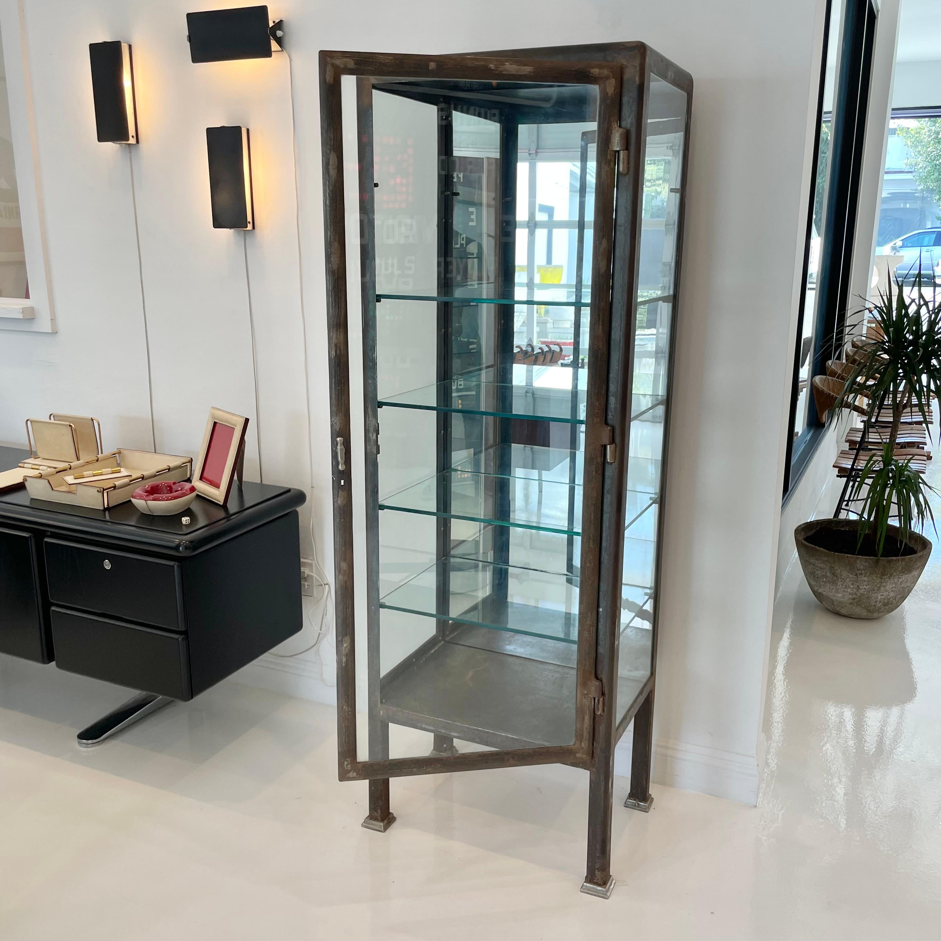 Slender Art Deco Vitrine made in the 1920s, Argentina. Rectangular frame sitting atop tapered legs. Original glass frame and door. Mirrored back. Four glass shelves. Original hardware. Extremely sturdy and substantial cabinet. Great for elevating