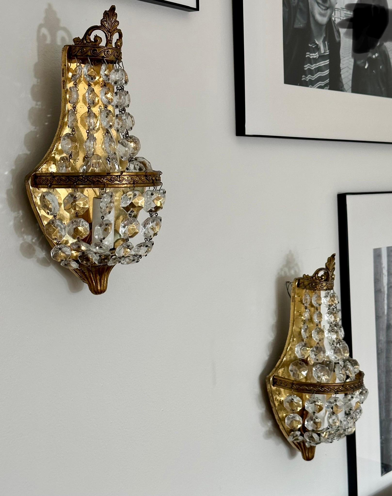 We are very pleased to offer a pair of enchanting sconces, circa the 1920s.  These Empire-style sconces exude an aura of class and elegance, transporting any room to a time of timeless sophistication.  Crafted with meticulous attention to detail,