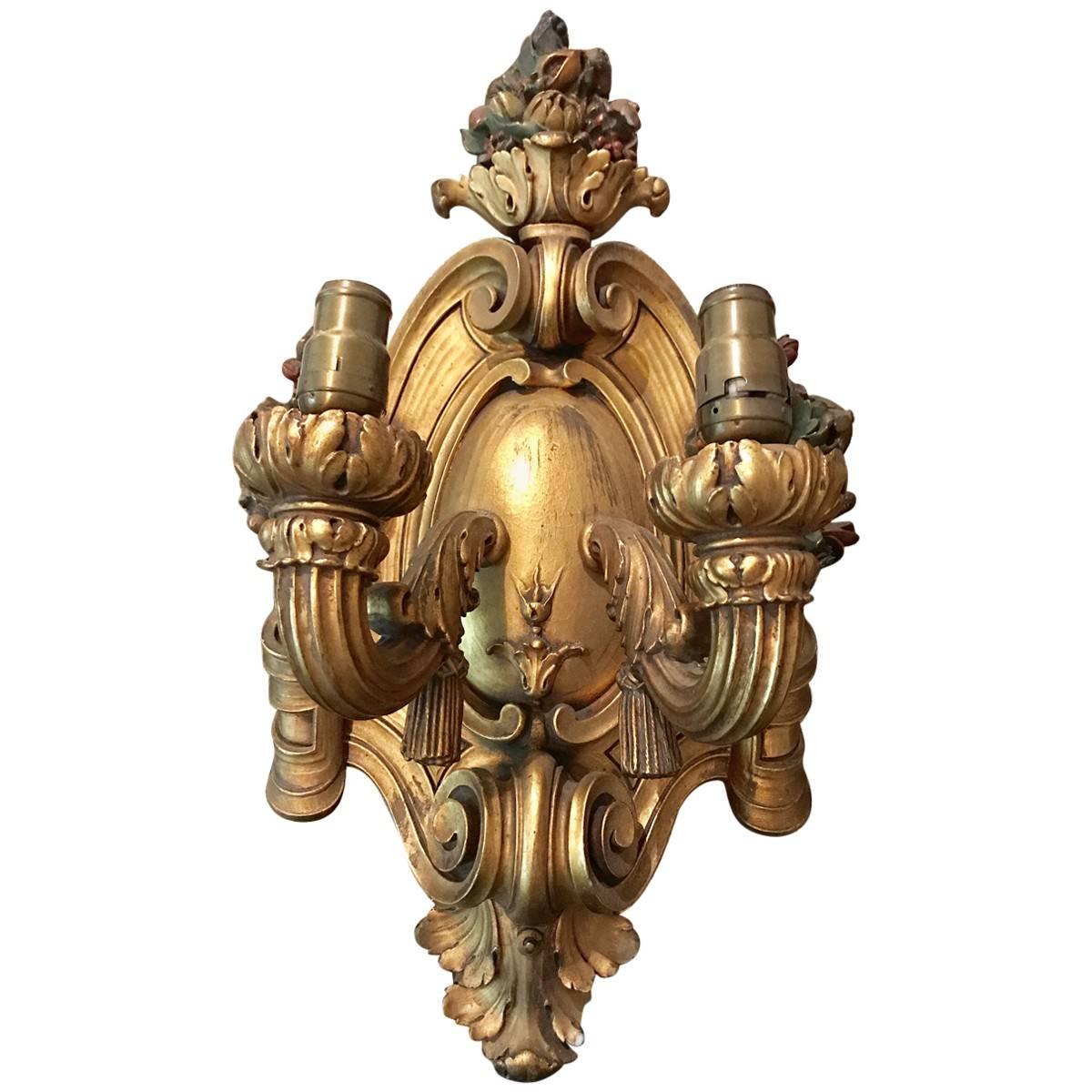 A collectible piece from bygone days, featuring the finest craftsmanship, materials, and design elements of its given era. Classic light fixtures with an elegant twist, this eye-catching pair of wall sconces is handcrafted from gilt. Two arms and