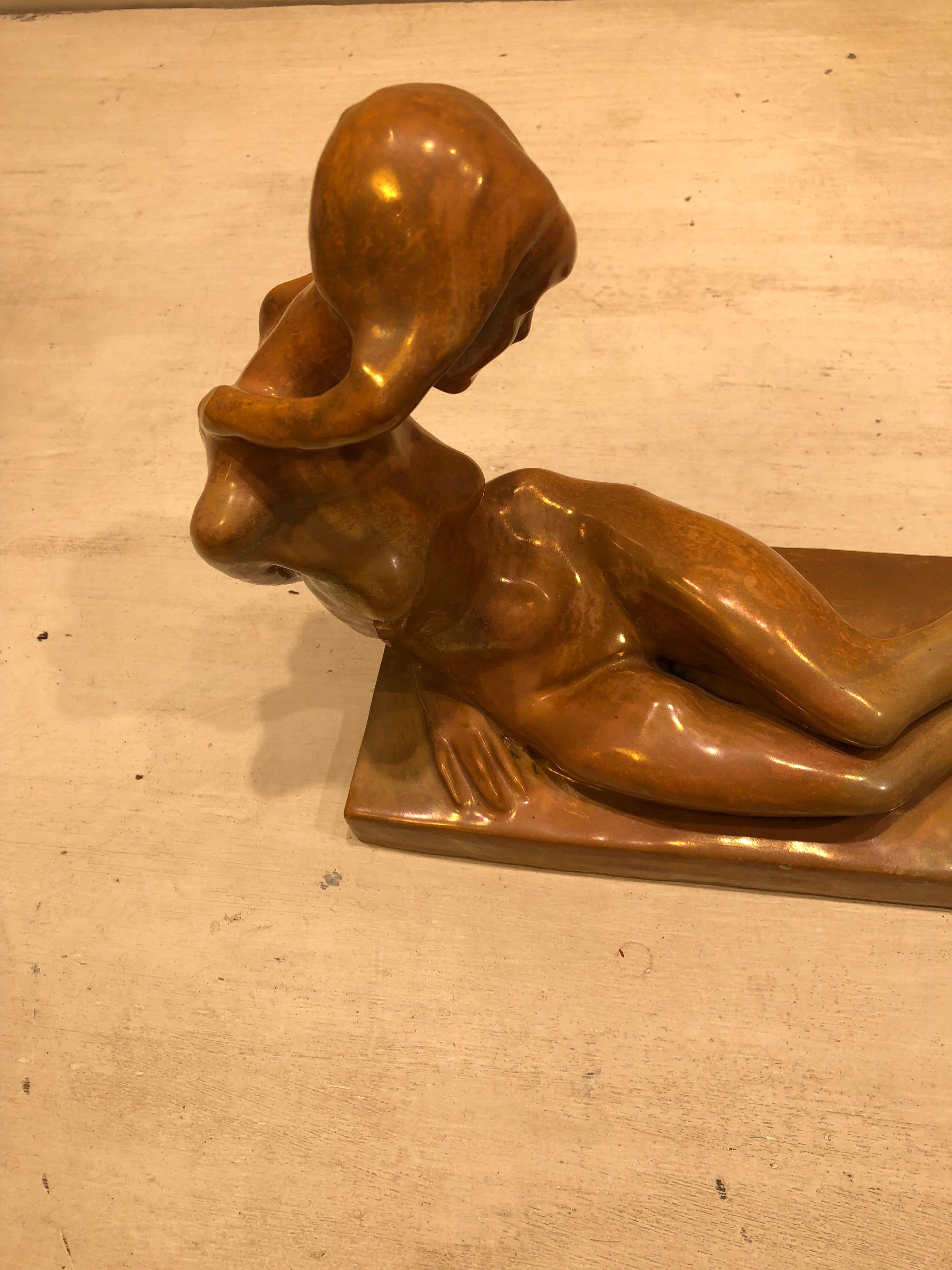 A beautiful ceramic sculpture with a gold/bronze irridescent finish of a reclining nude lady by the Italian artist Enrico Mazzolani. This piece is signed and in excellent condition.