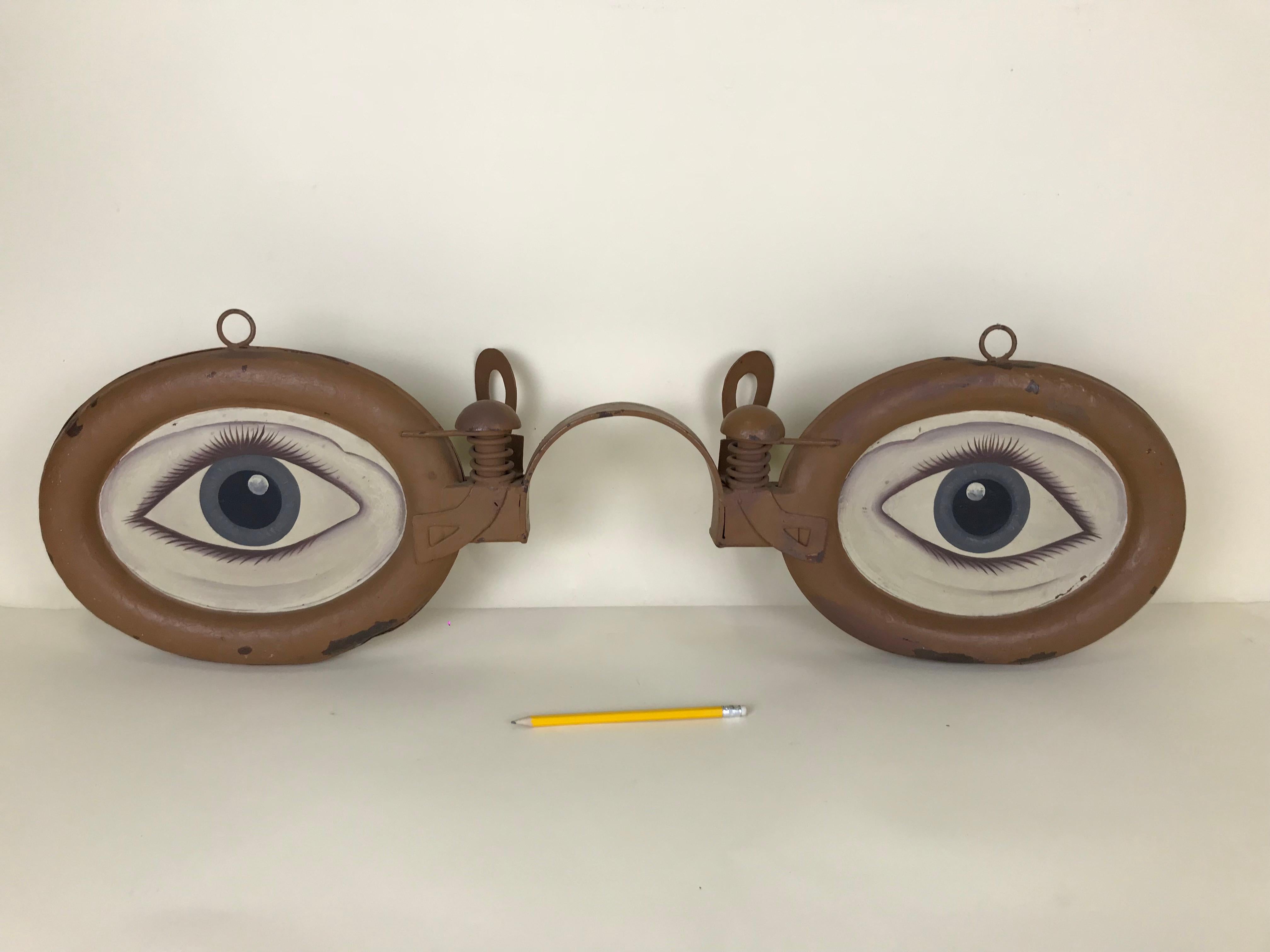 1920s Italian vintage metal double-sided optical shop sign in painted iron sheet. This stunning folk art sign representing in detail an eyewear sculpture featuring also painting of eyes on both sides. 

Dimensions eyewear: 86 W x 26 H x 13 D