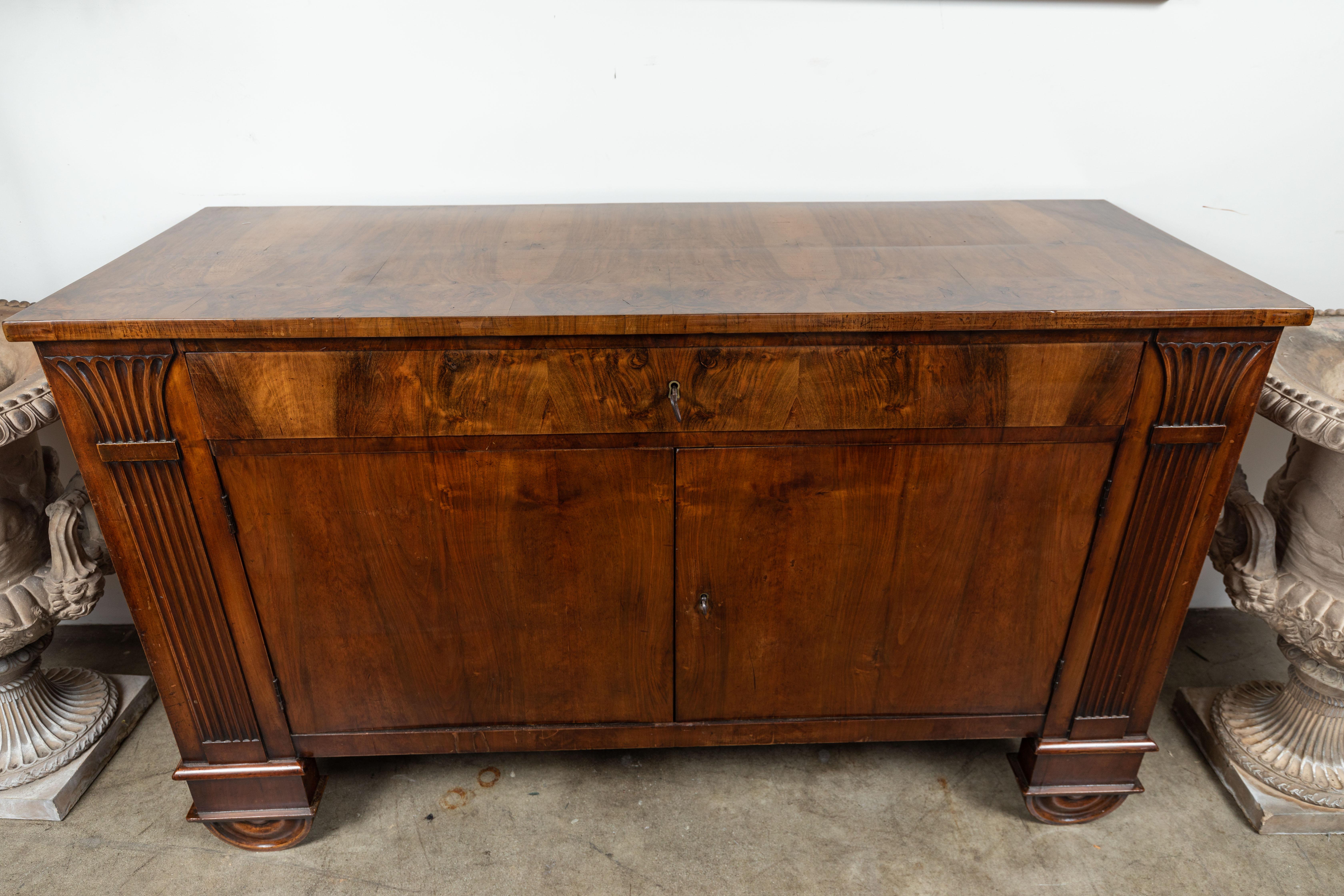 Beautifully carved, Liberty period, solid walnut buffet with book matched walnut veneer. A single drawer sits atop a two door base with both flanked by stylized, fluted, faux columns. The whole on unique, half-moon feet.