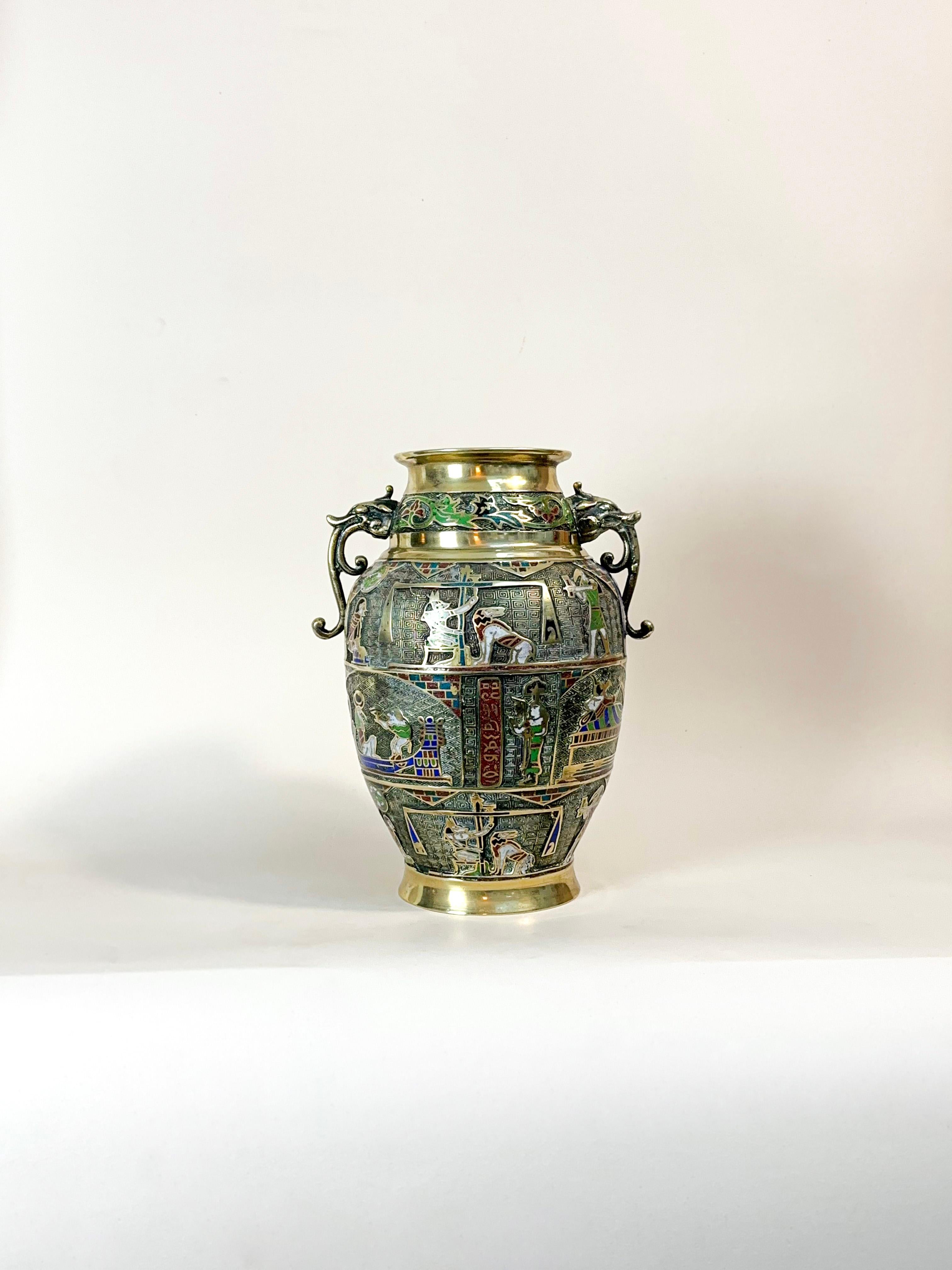 Large Art Deco era champlevé vase.

Brass urn-shaped vase from the 1920s, adorned with Egyptian motifs and scenes using the champlevé technique, featuring stylised dragon handles and a vibrant enamel finish.

Key Points:

Intricate champlevé enamel