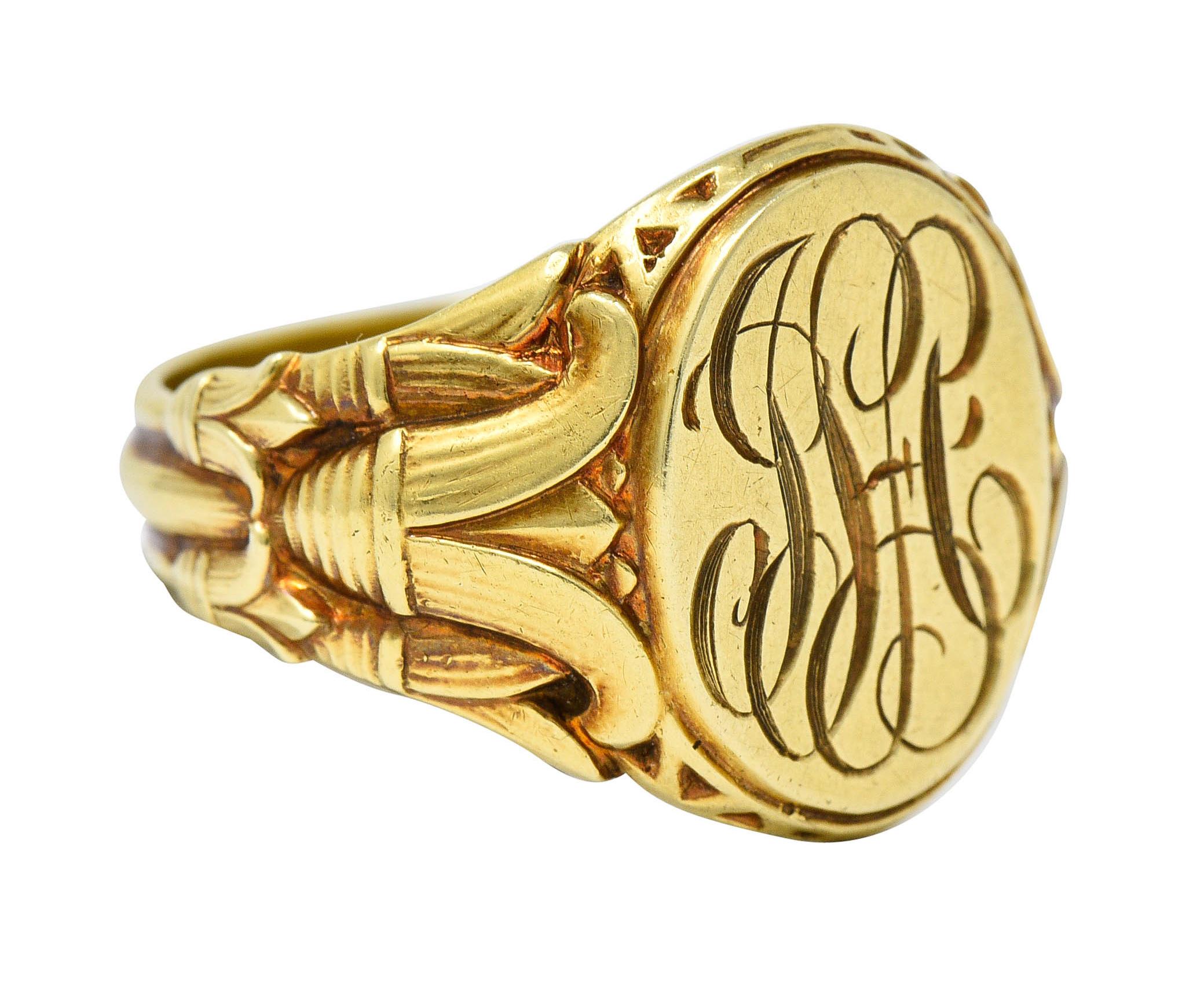 Signet style ring features an oval plane deeply engraved with a sinuous monogram

Flanked by highly rendered lotus flower shoulders - symbolic of rebirth

Stamped 14K for 14 karat gold

Fully signed Lambert Bros

Circa: 1920s

Ring Size: 8 3/4 &