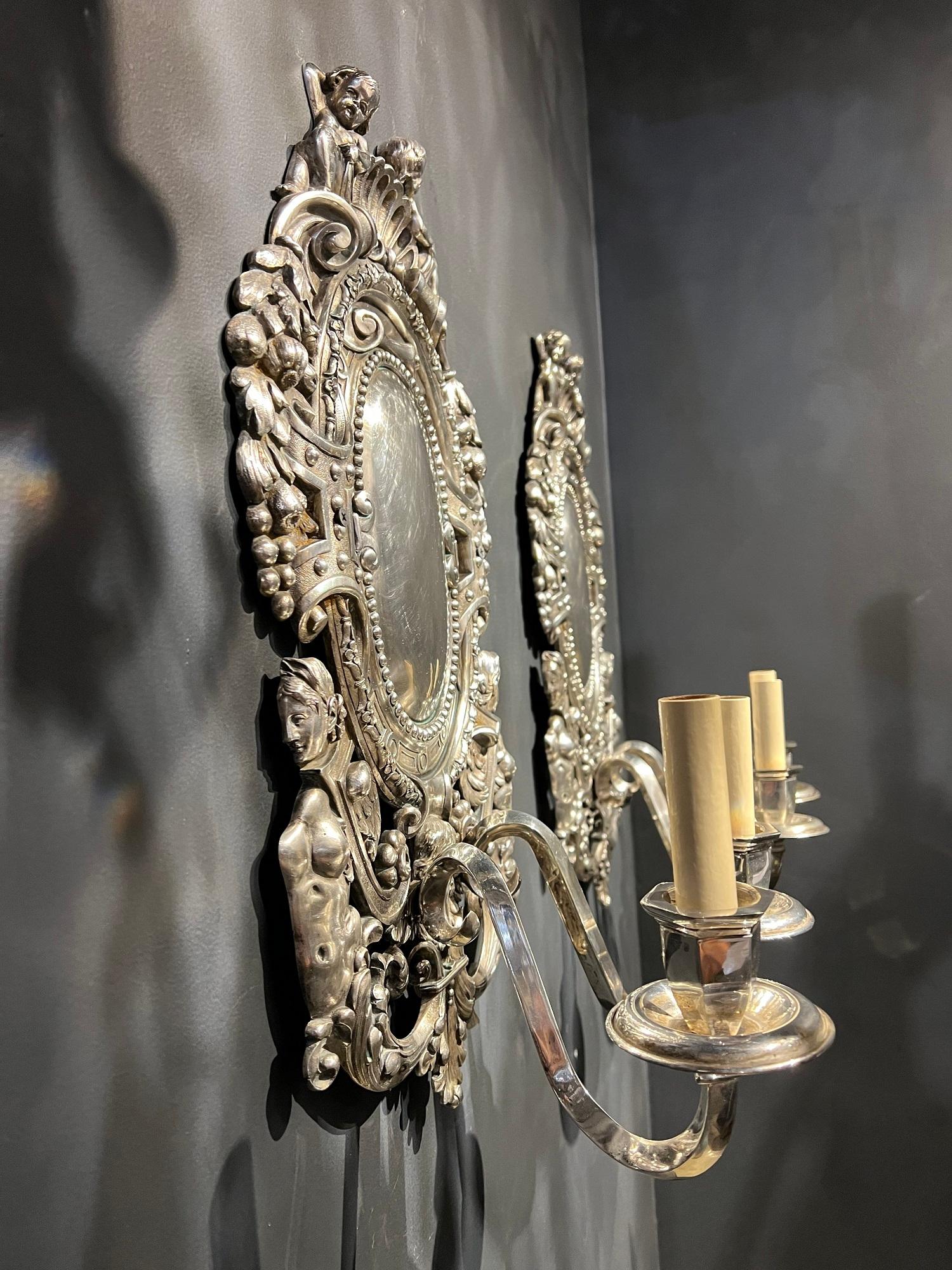A pair of circa 1920’s Caldwell neoclassic style large sconces with cherubs and mermaids on design and two arms for lights