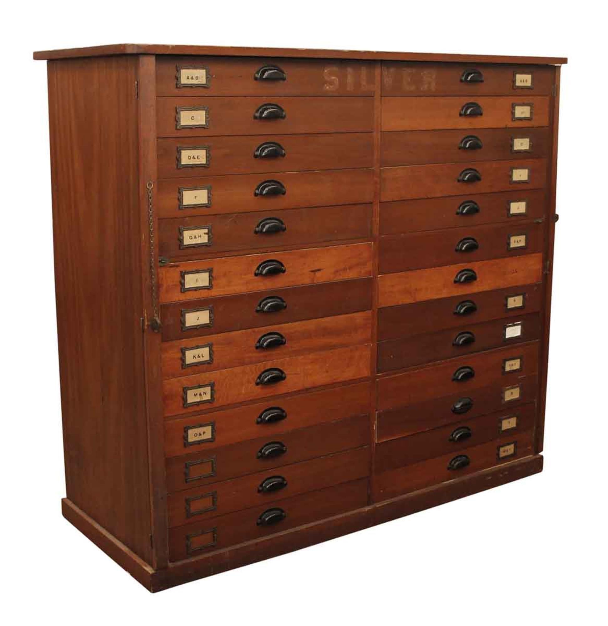1920s large 26-drawer wooden flatware cabinet from an early 20th century New England company that made flatware. It originally locked from either side by a wood bar over the edge of drawers. The original locks are still attached, but there is no