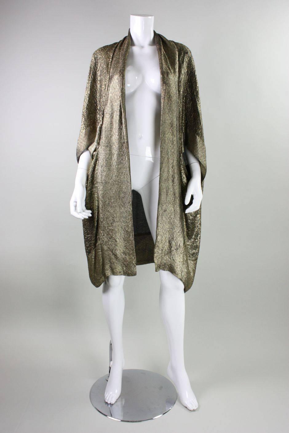 Vintage coat by Liberty of London dates to the Art Deco era during the 1920's.  It is made of fine gold lame fabric with an allover geometric motif.  Shawl lapel.  A series of pintucks at the back neck provide volume. No closures.  Unlined.
No size