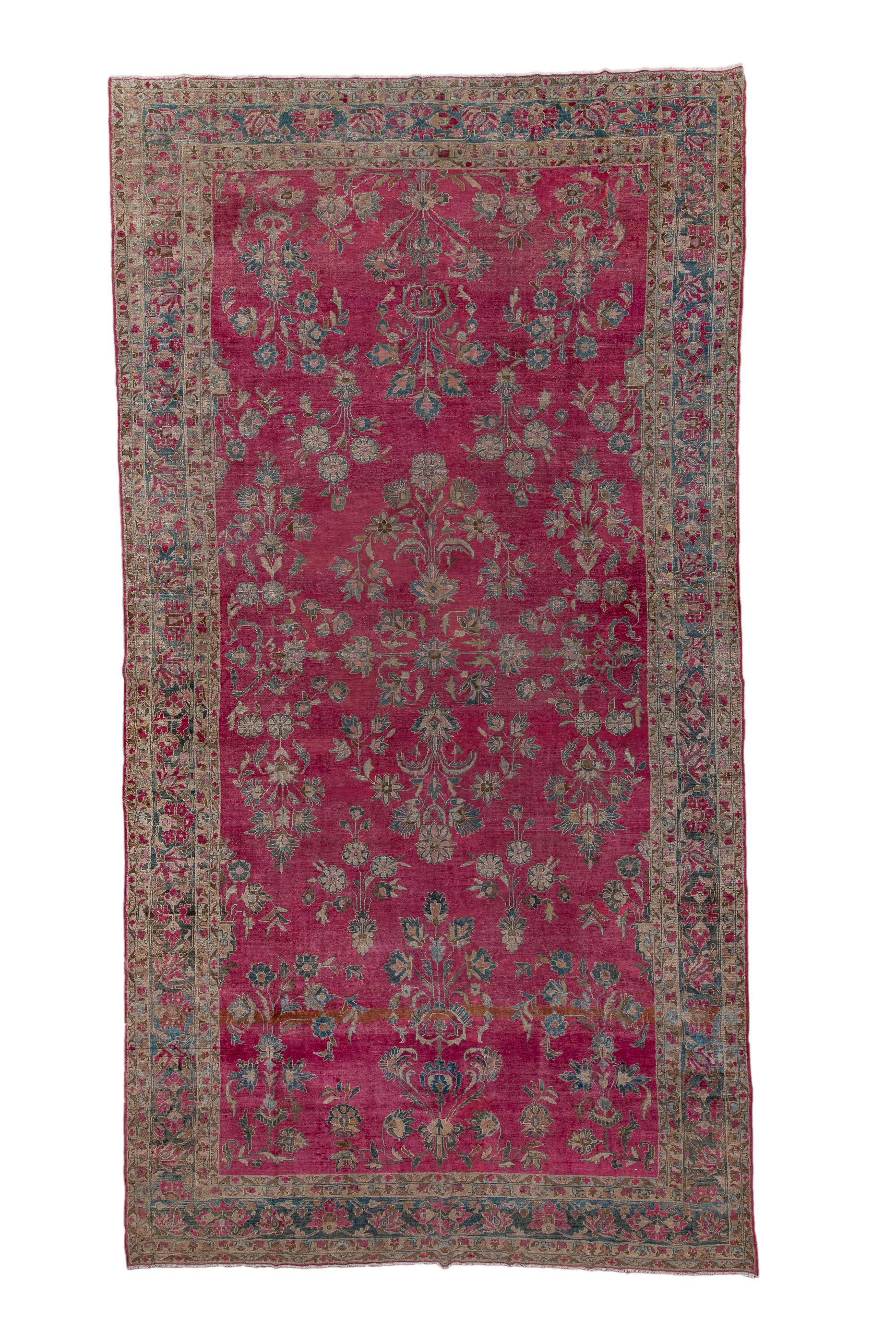 The mulberry red field of this village carpet hosts a selection of detached floral spray in the “American Sarouk” manner. A central radiating eight palmette motif centres the pattern. Border of tilted and upright petal palmettes. Allover details in