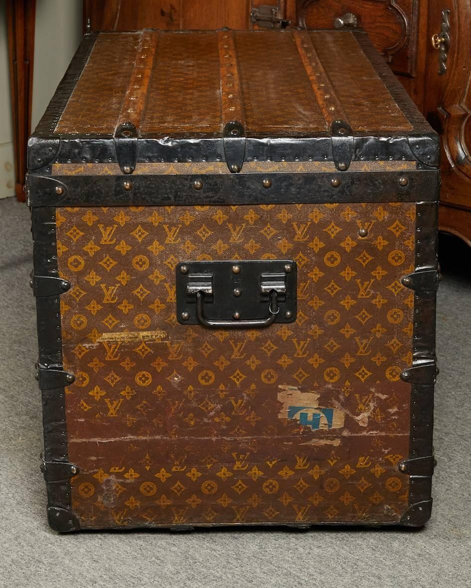 1920s Louis Vuitton steamer trunk with studded black metal trim and all inscribed L.V. with surface fitted by wooden trusts. Accompanied inside with a two-tier compartments.
 